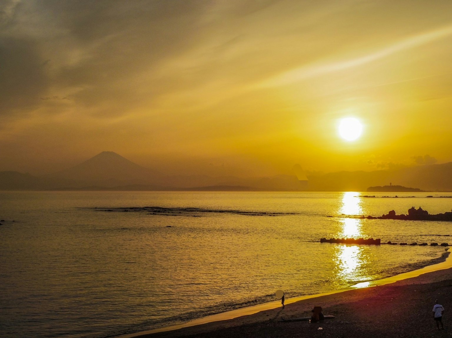 美丽的日落映照在海面上，山和海岸的轮廓可见