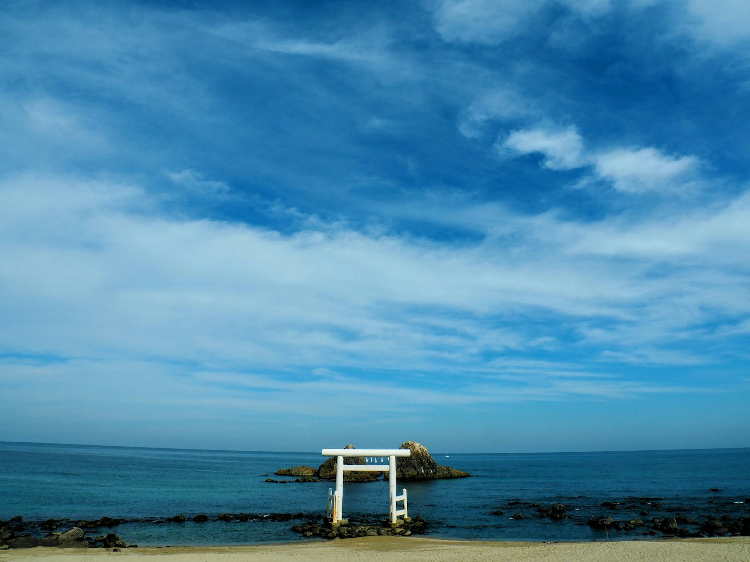 Torii vicino al mare blu e al cielo con una costa rocciosa