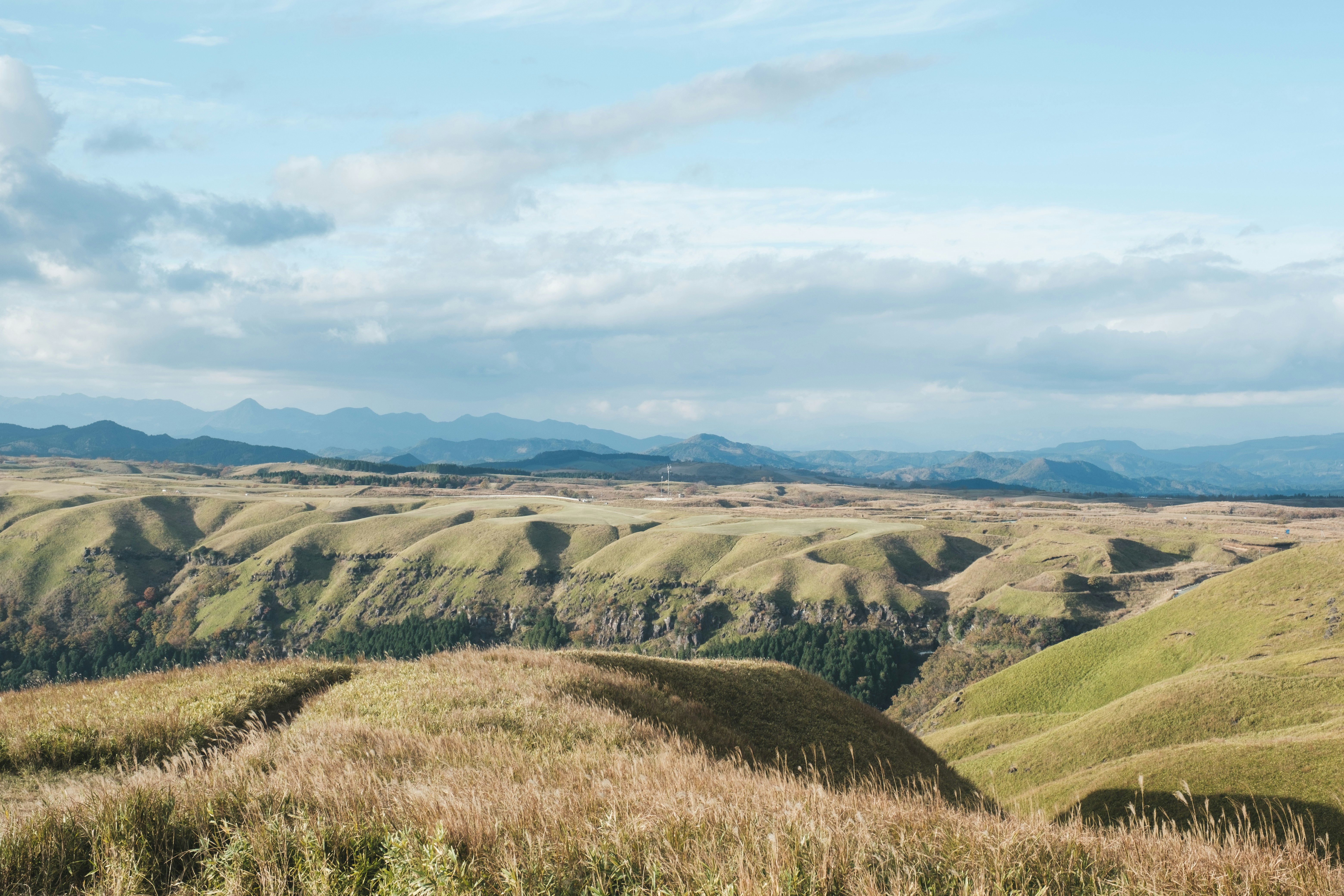 Berglandschaft mit sanften, grasbewachsenen Hügeln und fernen Bergrücken