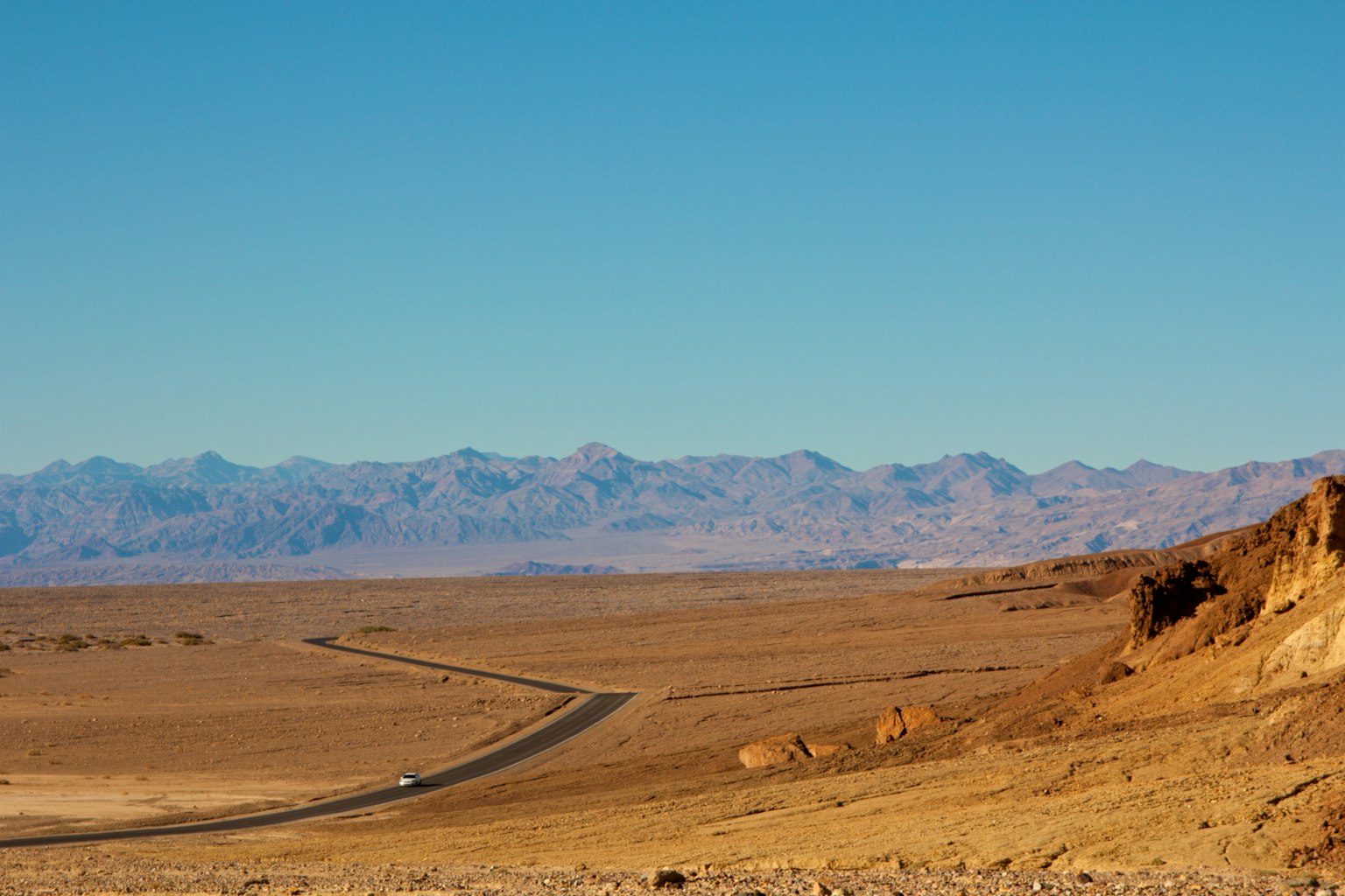 Ampio paesaggio desertico con cielo blu strada tortuosa e montagne lontane