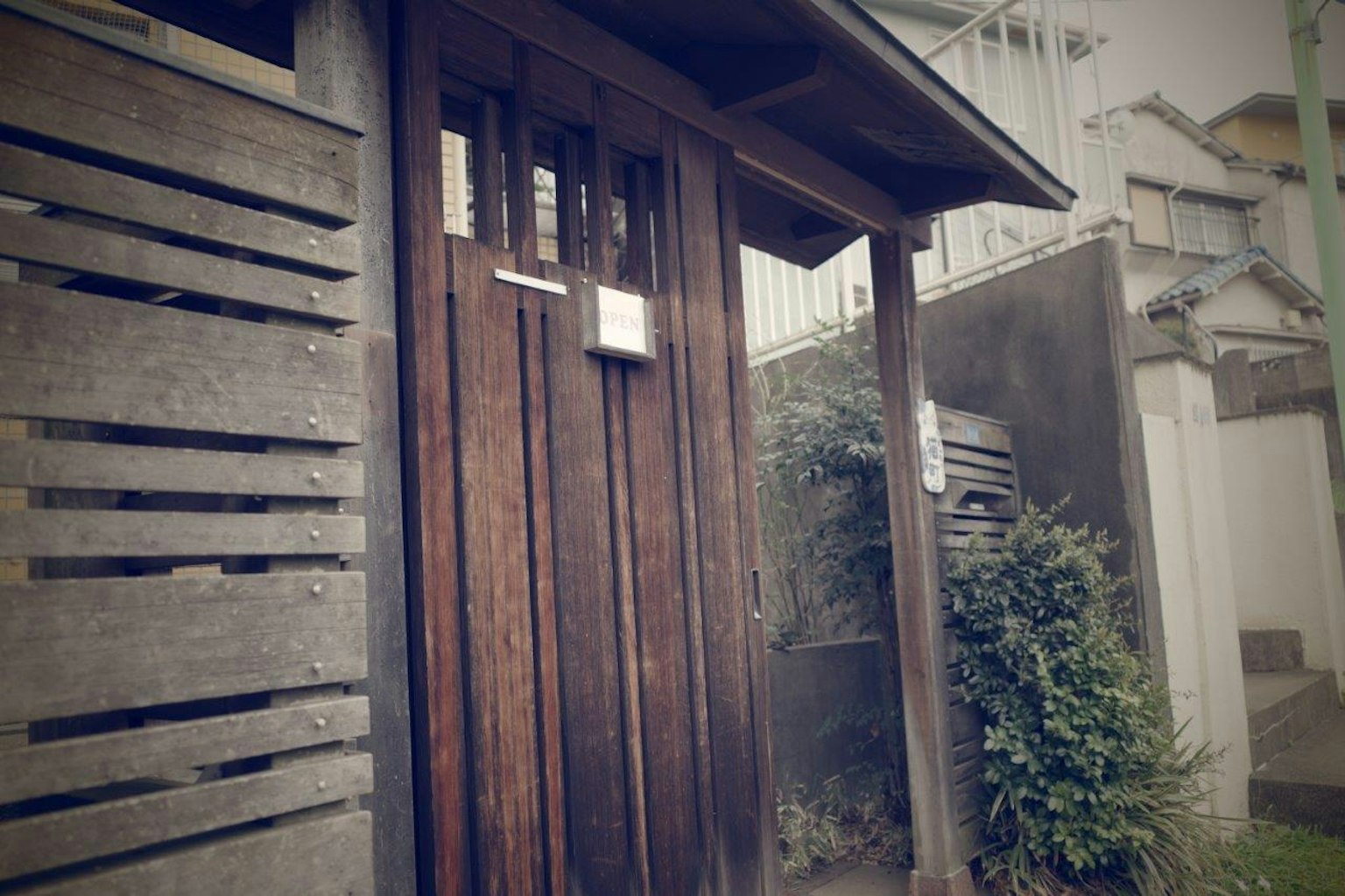 Entrada de una casa con puerta de madera y plantas alrededor