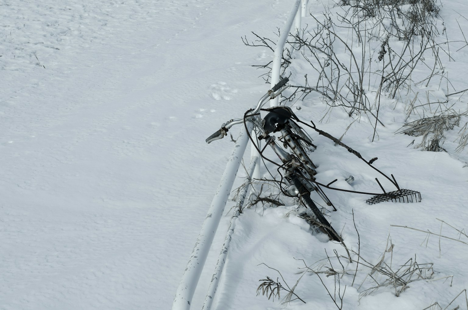 Un marco de bicicleta antiguo y hierba seca en un suelo cubierto de nieve