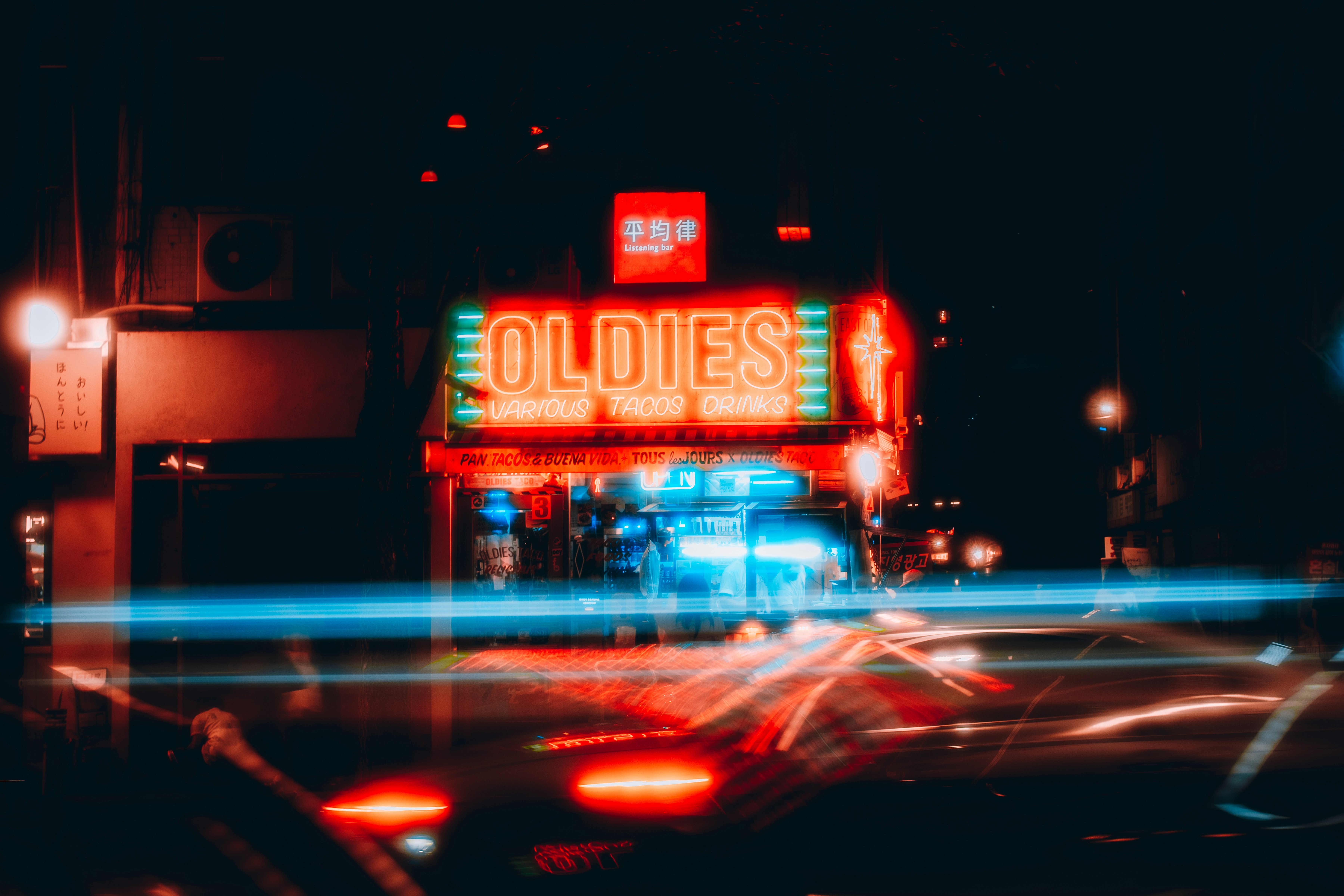 夜の交差点で光る「OLDIES」看板と車の流れる光