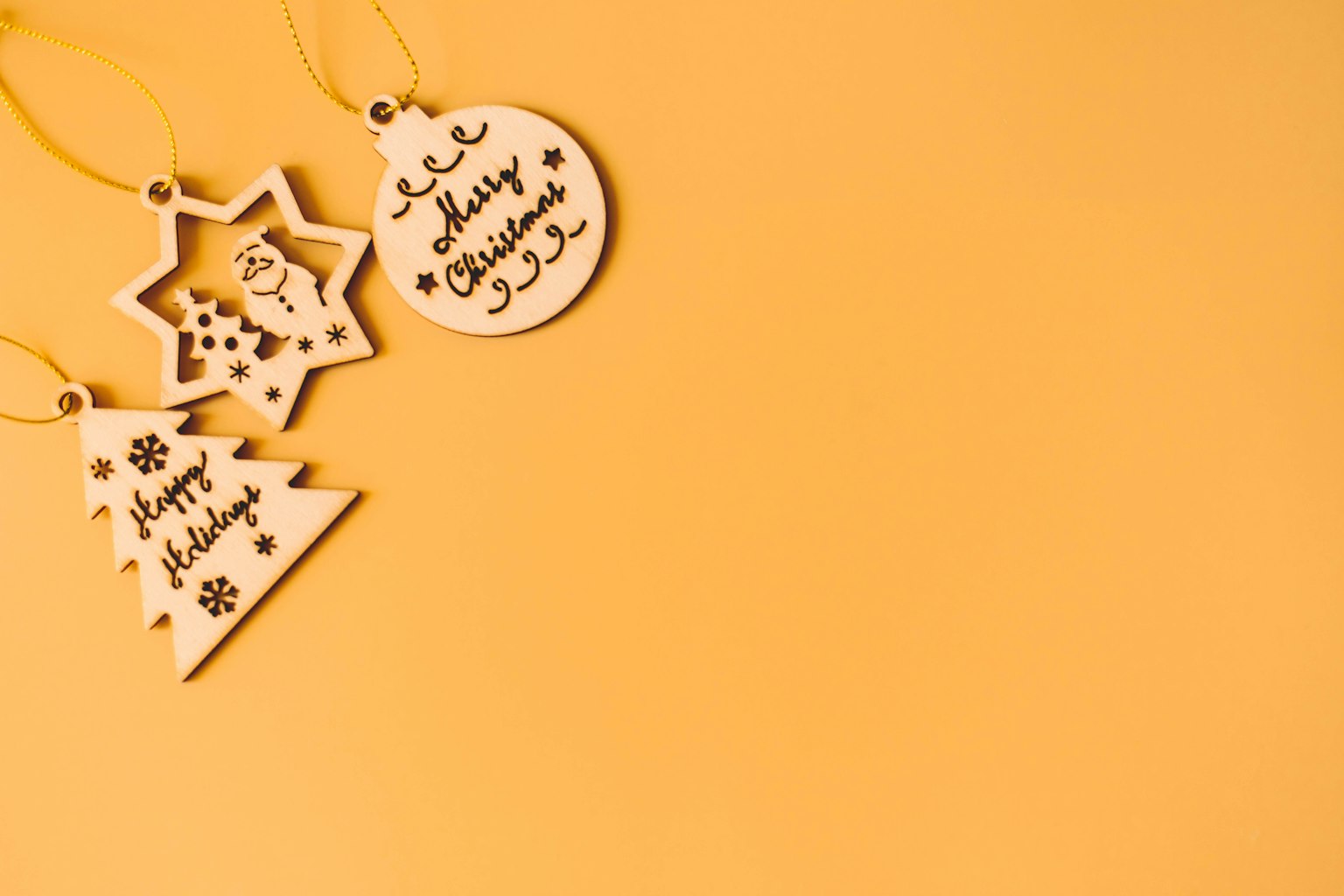 Wooden Christmas ornaments in star and tree shapes against a yellow background