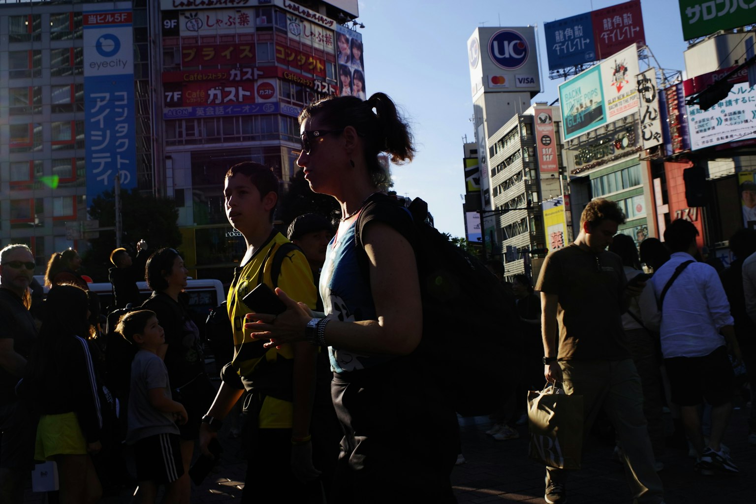 Silhouettes of people walking in a bustling urban area with buildings