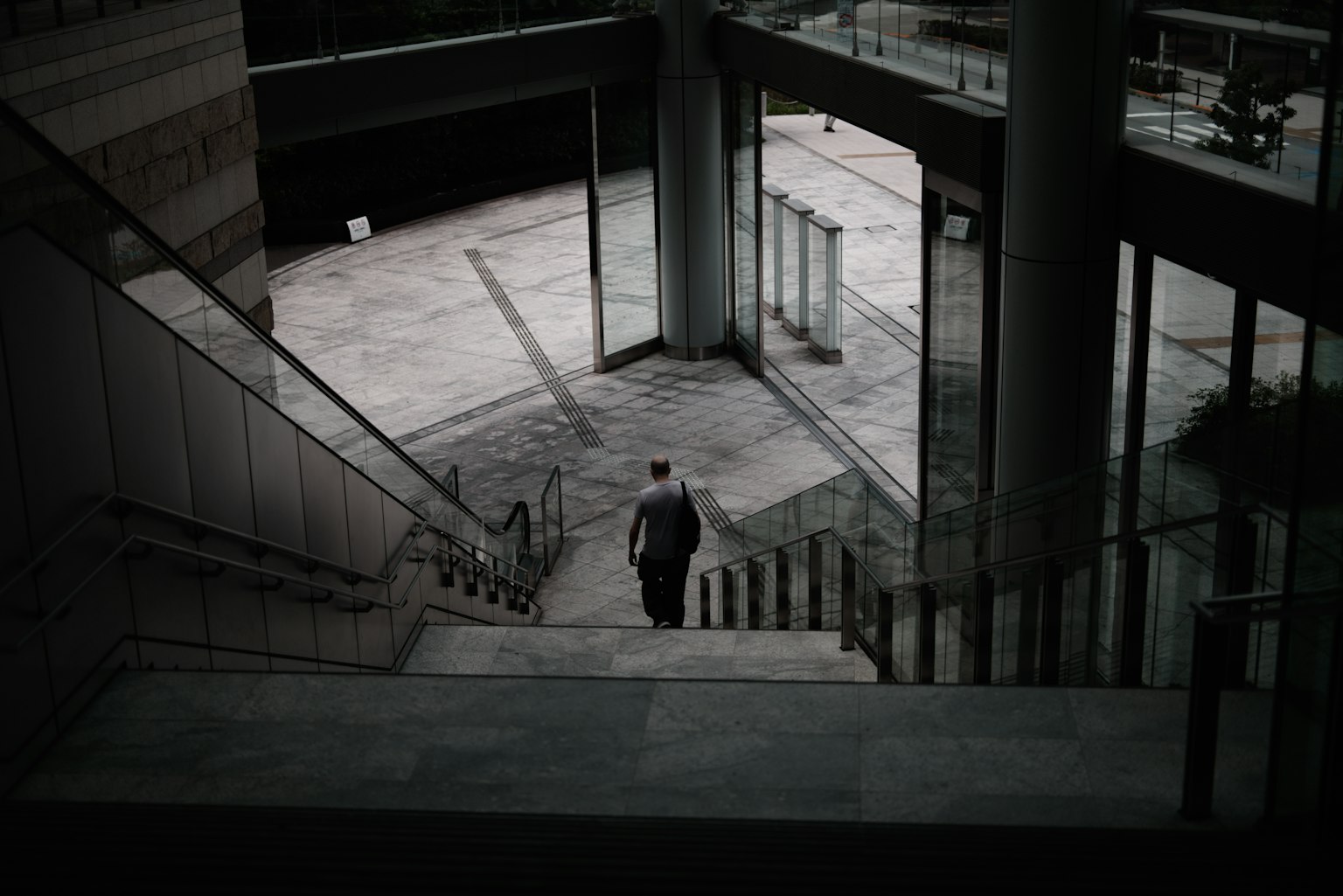 Silhouette of a person descending stairs with striking contrasts of shadows in a modern building interior