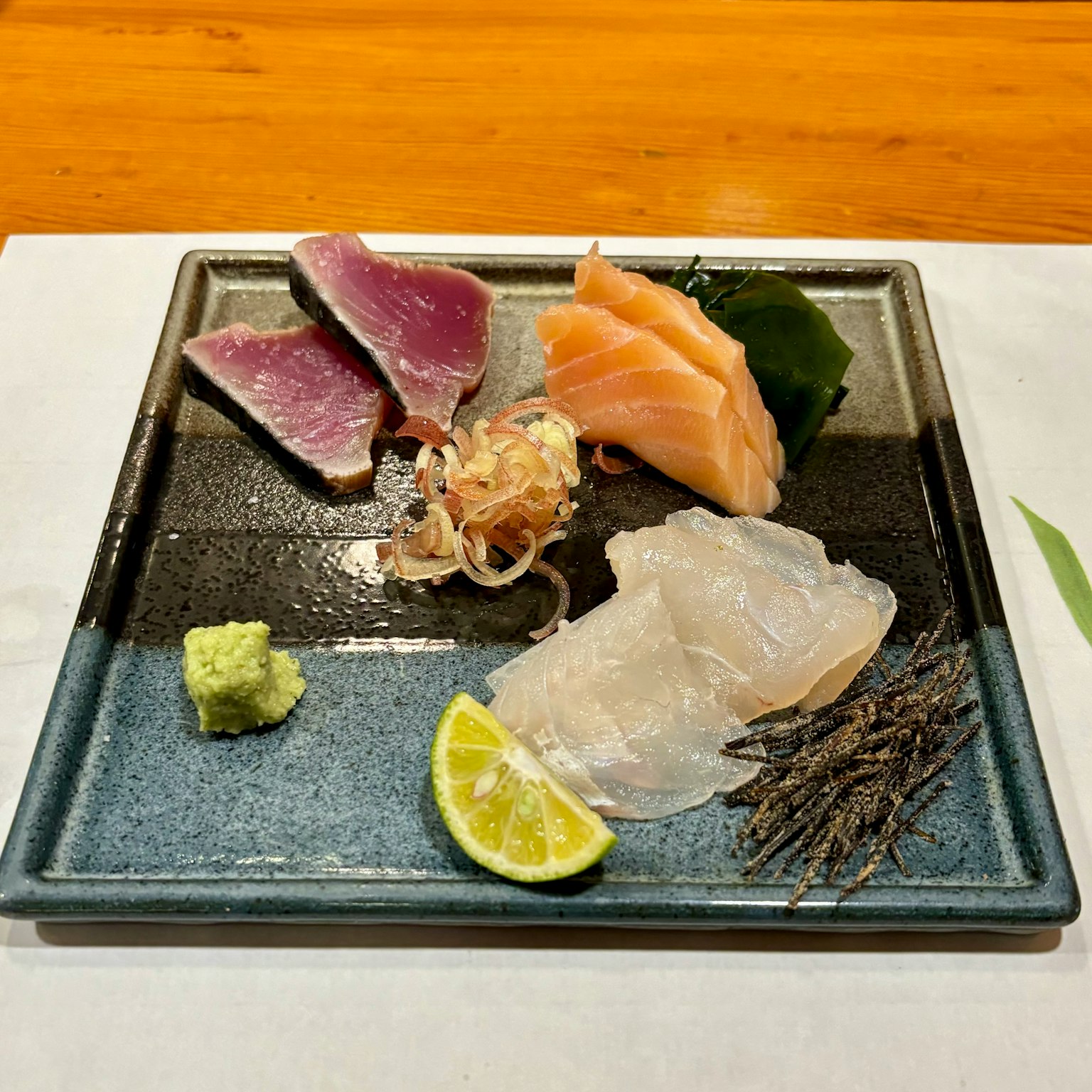 新鮮的刺身盤上有鮭魚、吞拿魚和白魚，配有青檸和芥末