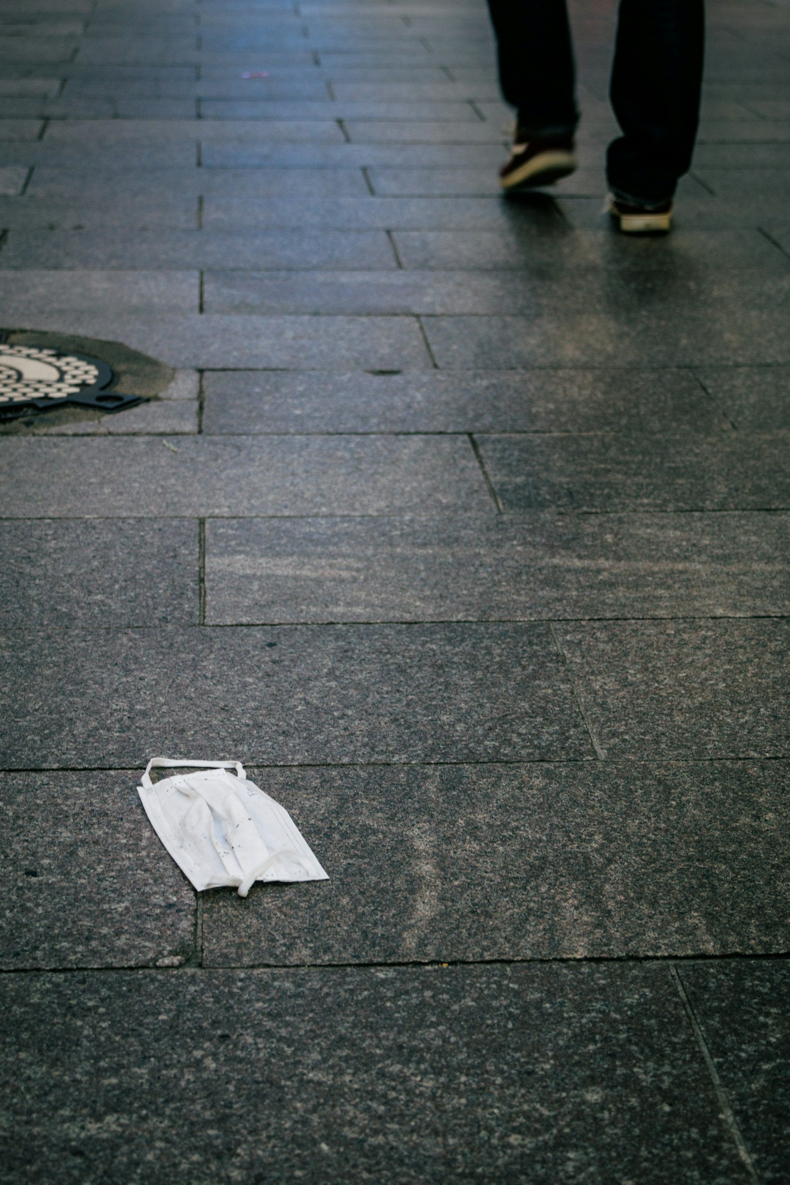 Ein weißes Papier auf dem Boden mit den Füßen einer Person, die in der Nähe geht