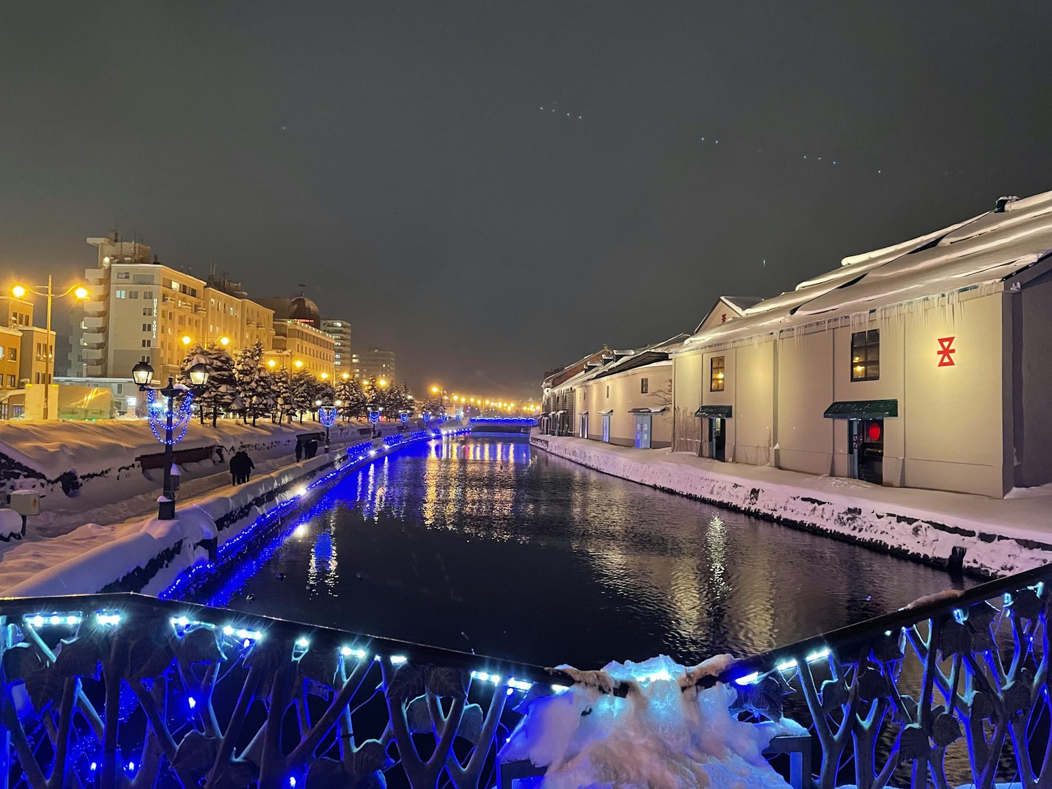 A beautiful winter scene with a snow-covered river and city lights at night