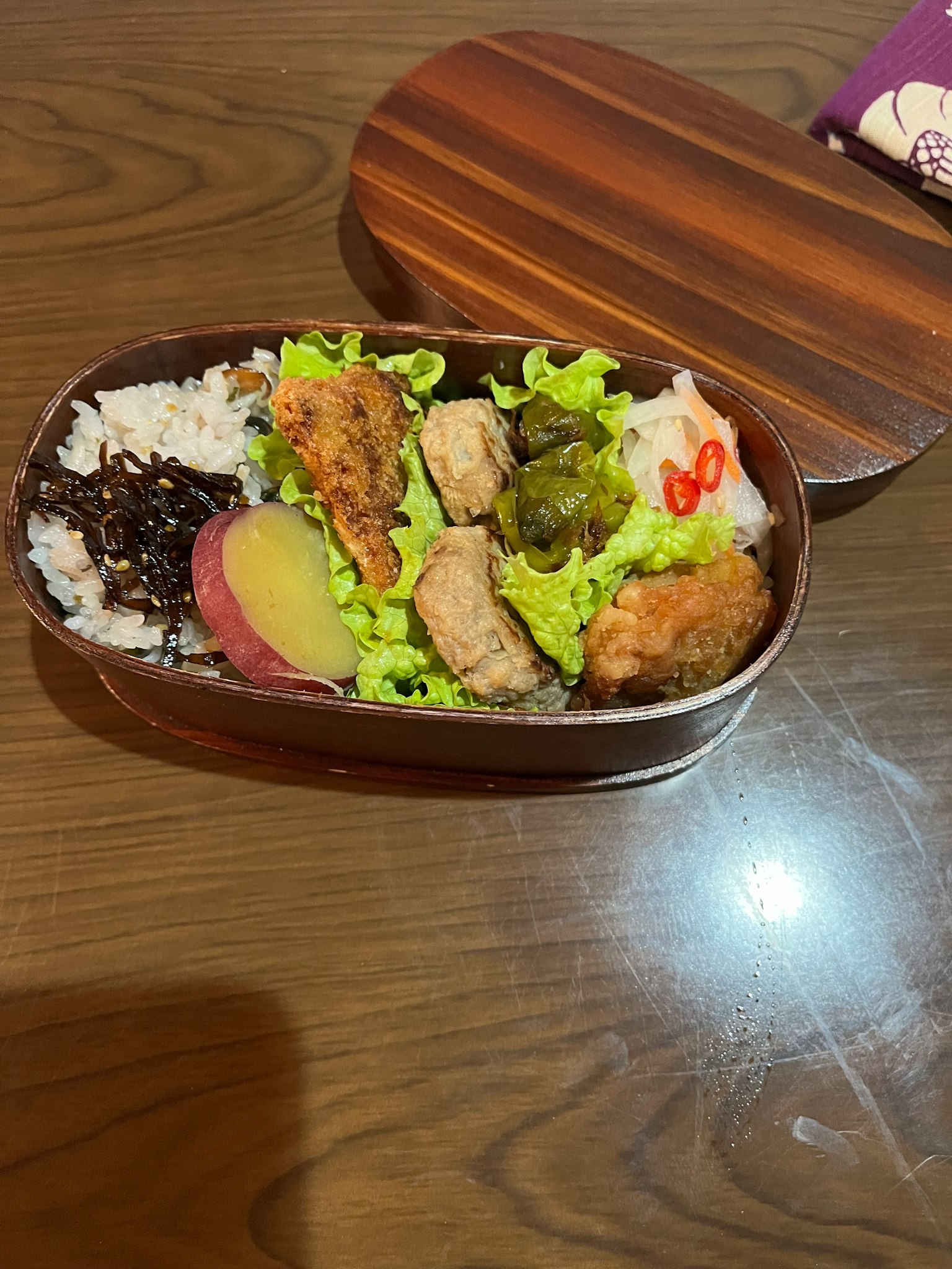 Bento box with rice, chicken, lettuce, sweet potato, and red chili