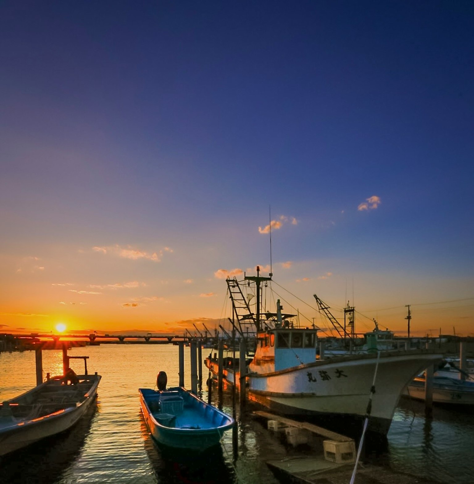 View of boats and fishing vessels docked at a harbor during sunset