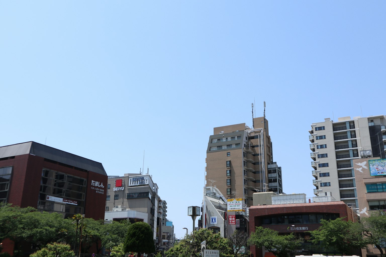 ทิวทัศน์เมืองที่มีตึกระฟ้าและอาคารเตี้ยใต้ท้องฟ้าสีฟ้าใส