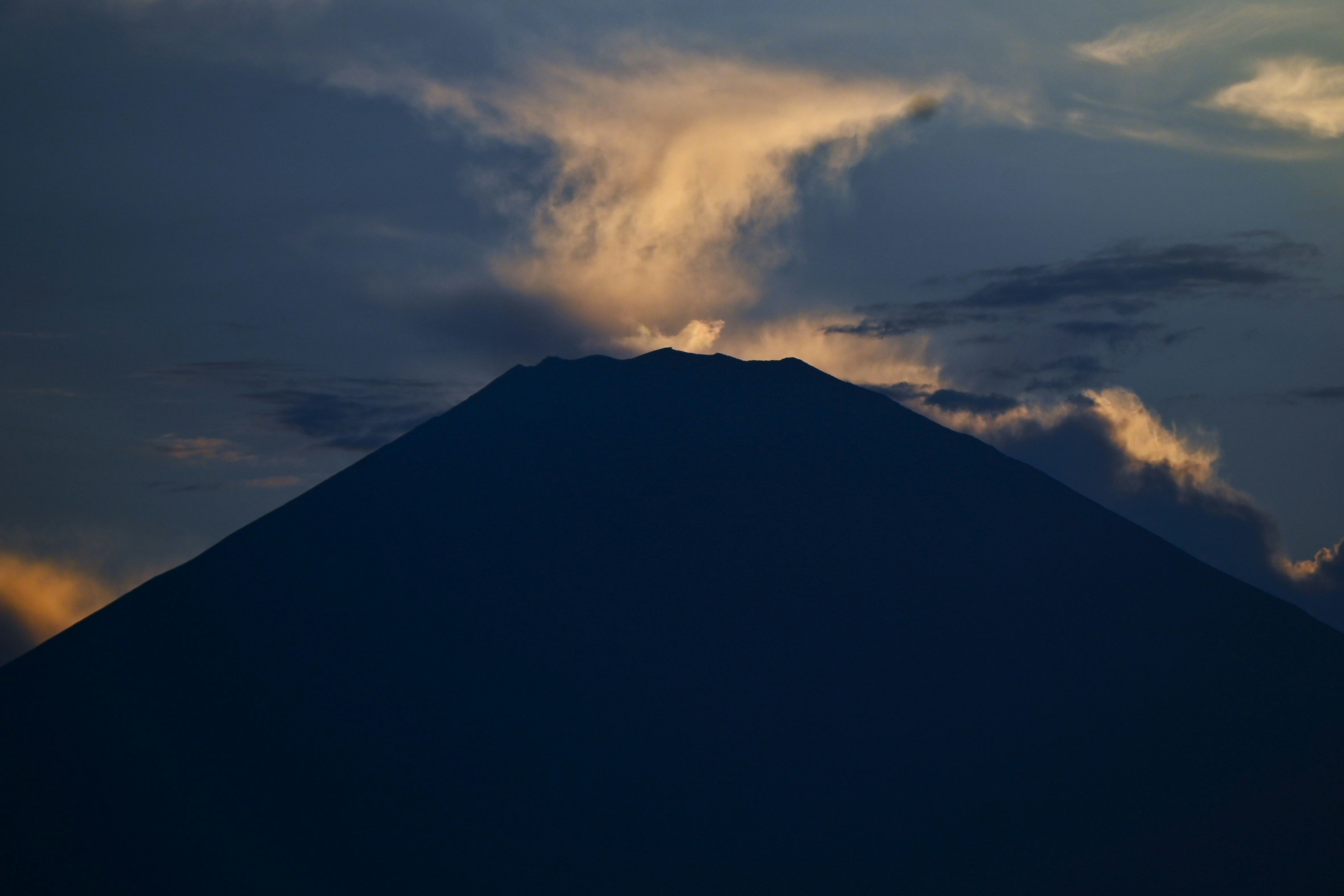silhouette de montagne éclairée par des nuages au coucher du soleil