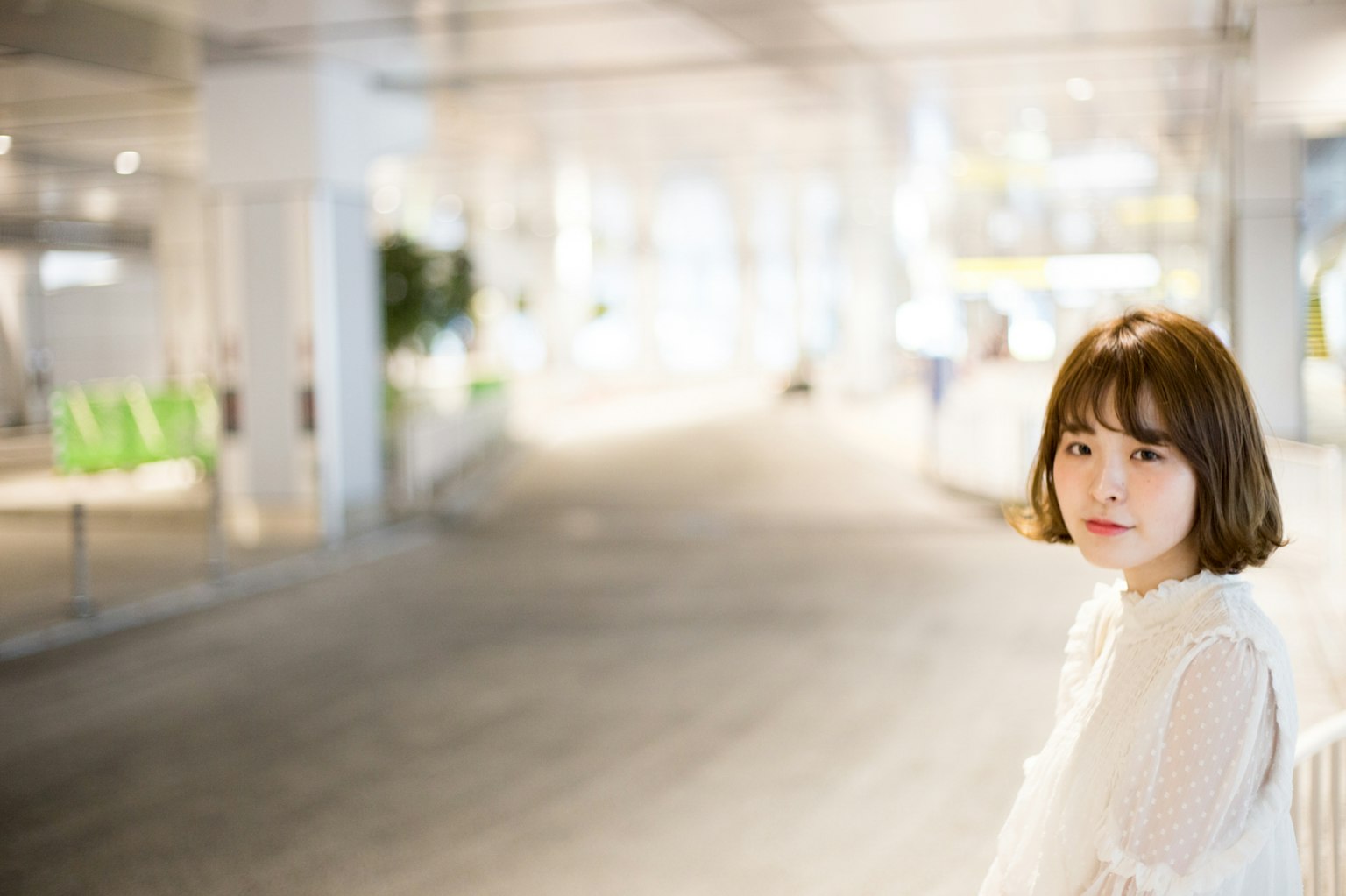 Retrato de una mujer con cabello corto vestida con una blusa blanca en un fondo brillante