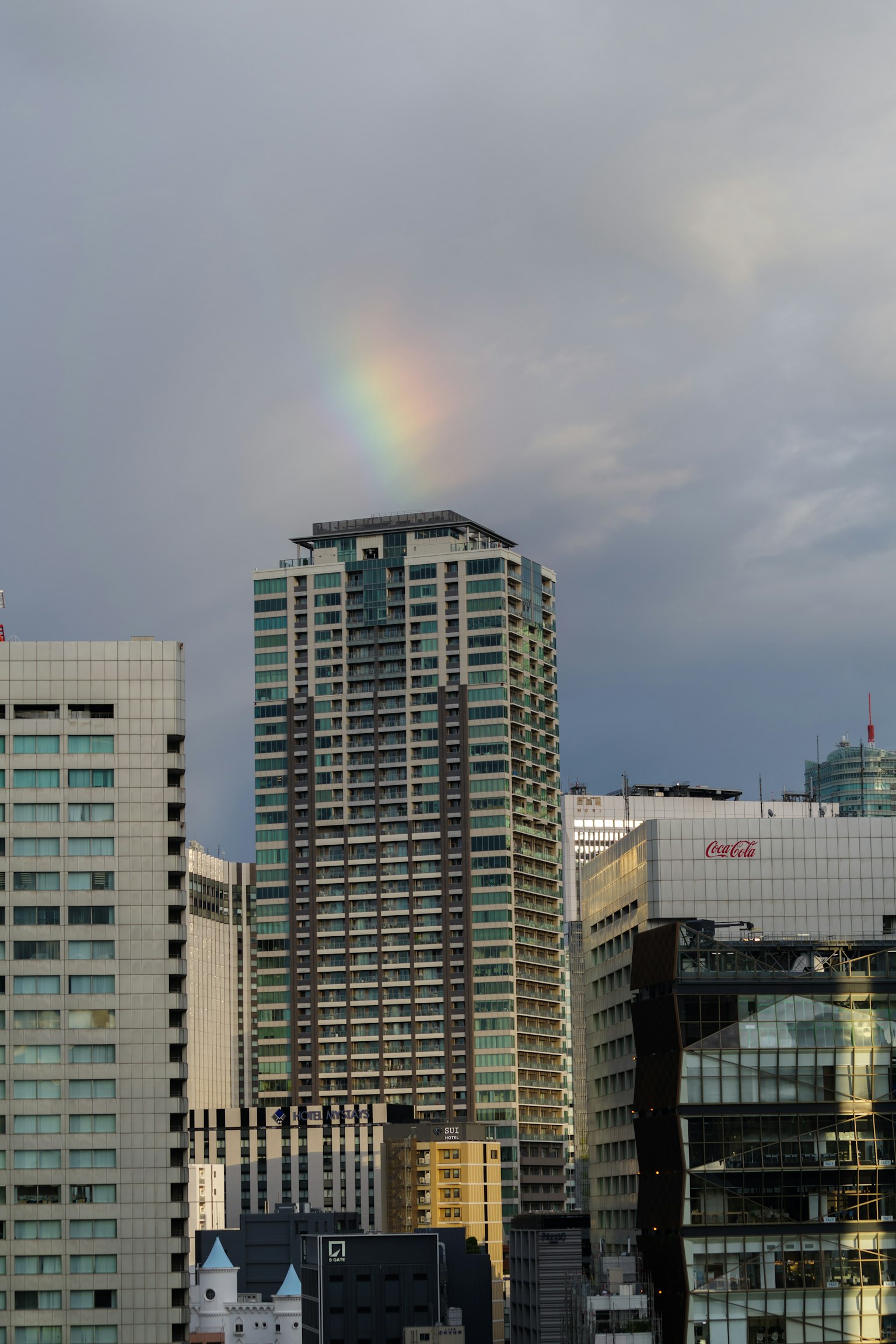 Arcobaleno sopra un grattacielo con cielo nuvoloso
