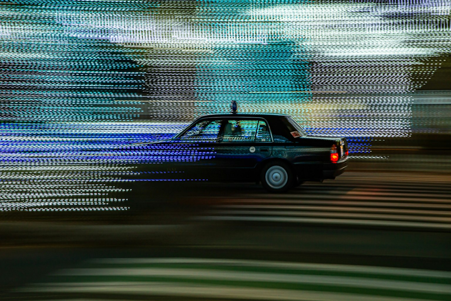 Un taxi noir filant à travers des traînées de lumière vibrantes