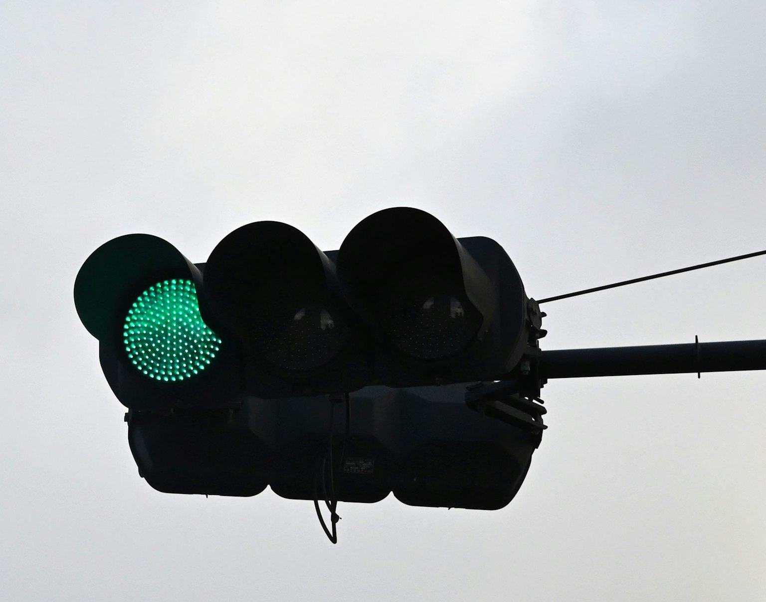 Lampu lalu lintas hijau menyala di langit berawan