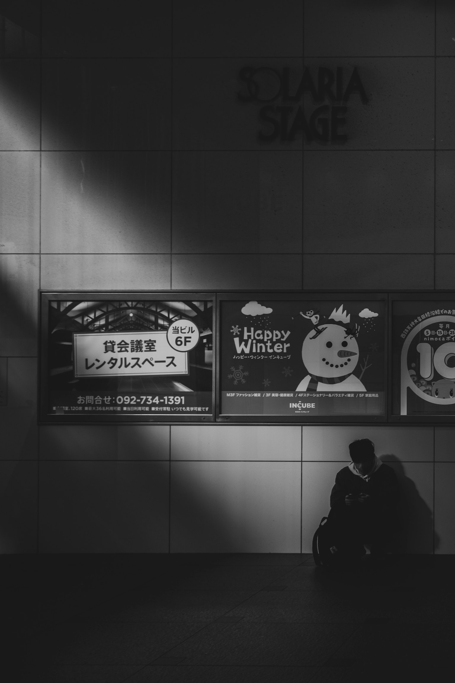 Couple sitting in shadow against a wall with advertisements