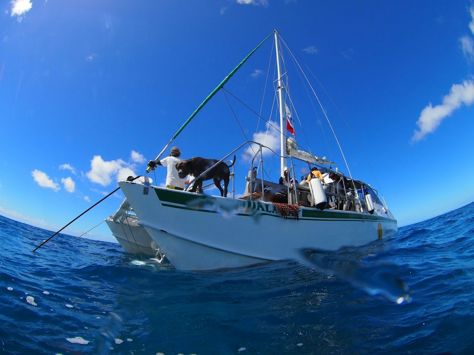 Un barco con miembros de la tripulación flotando en el océano bajo un cielo azul