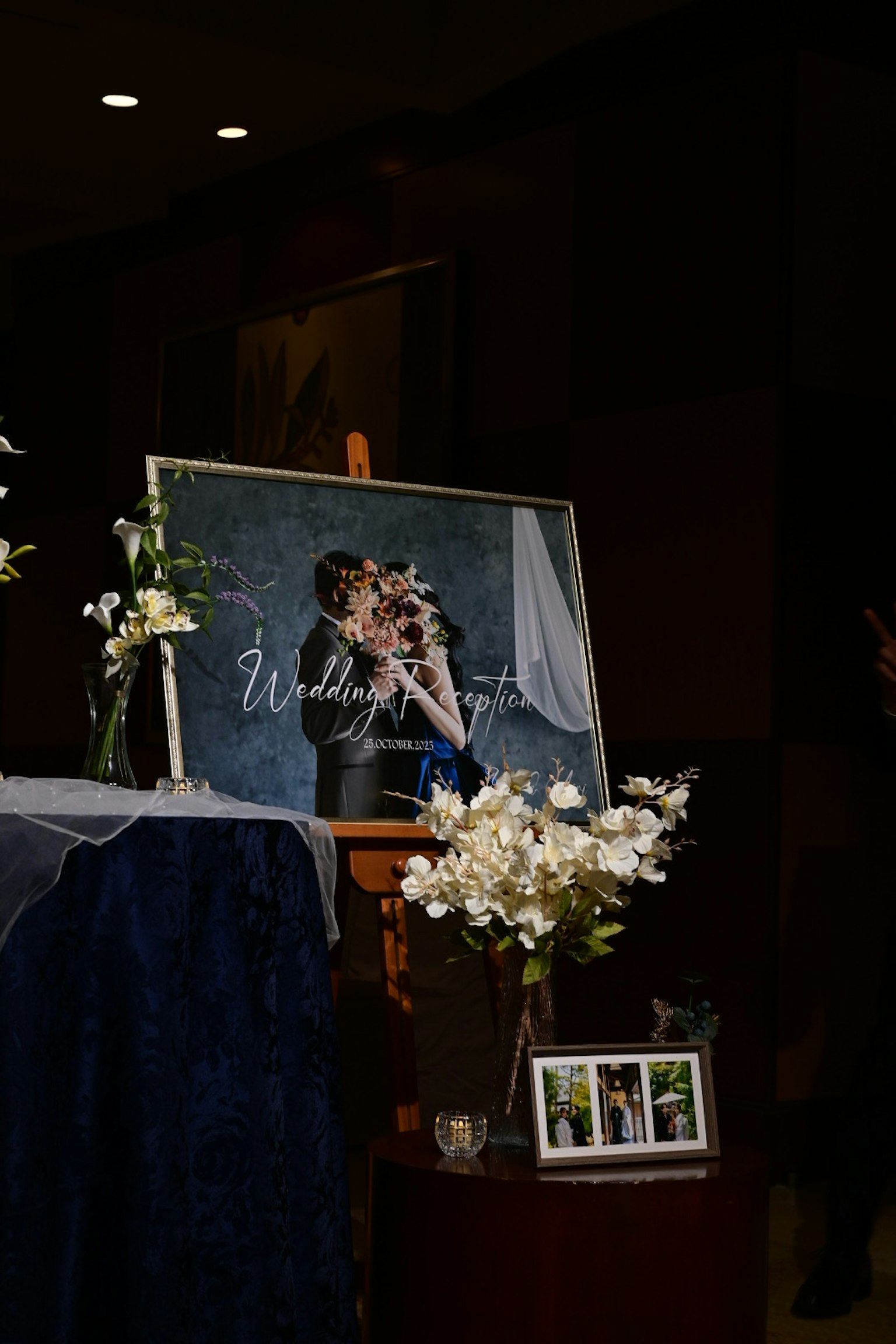 結婚式の写真が飾られたテーブルに白い花と青い布が置かれている