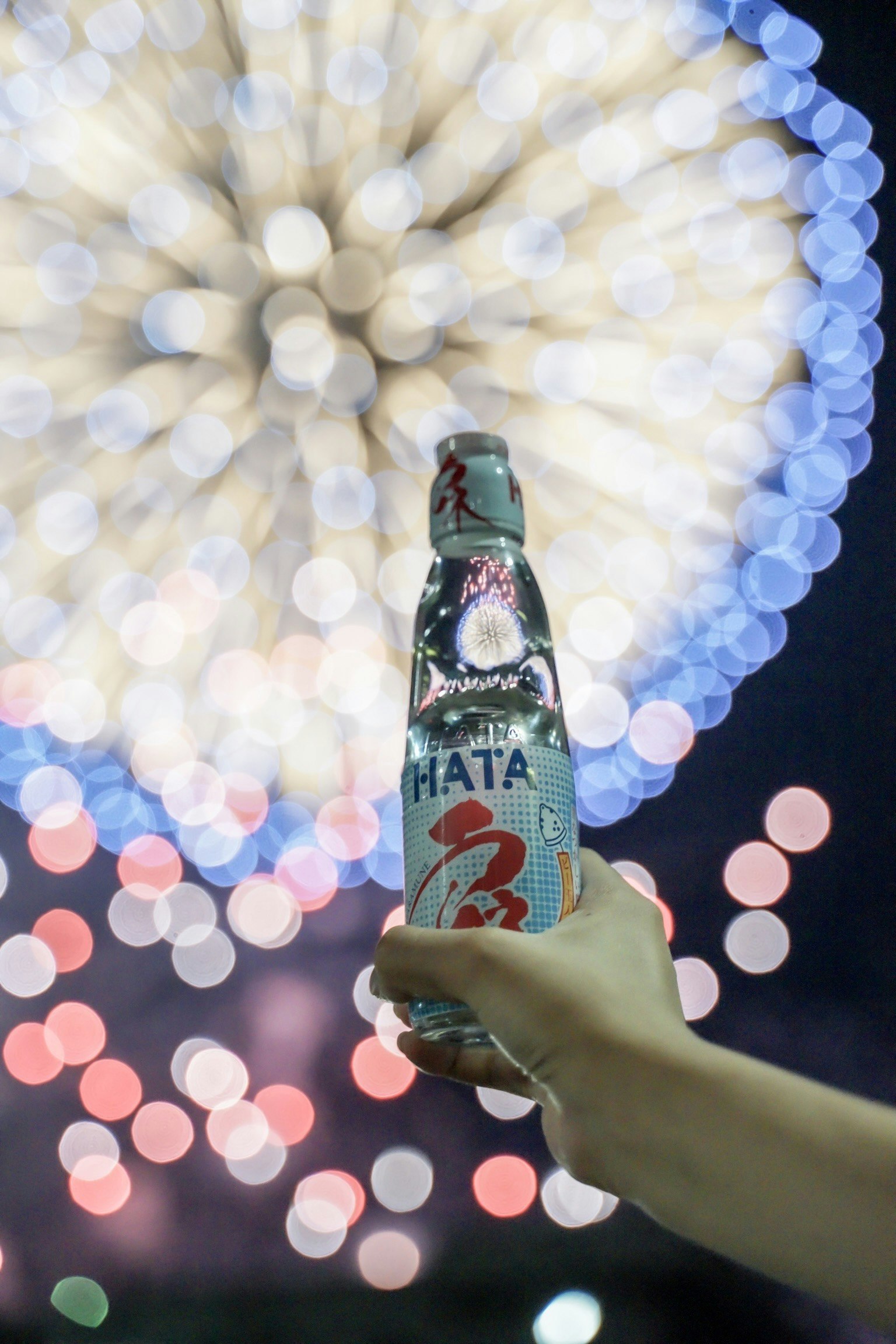 bouteille de bière tenue à la main avec des lumières bokeh colorées