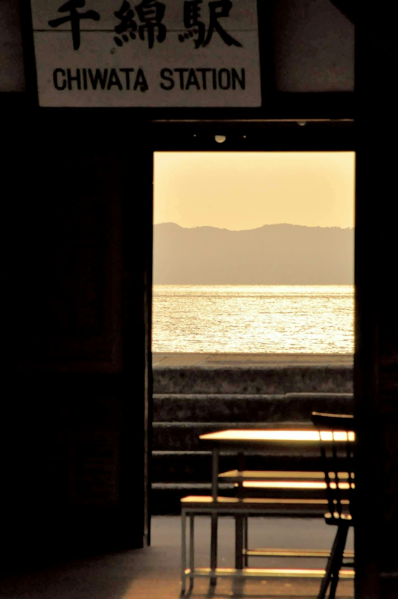Porte ouverte avec un panneau pour la station Chiwata montrant une vue sur la mer et les montagnes