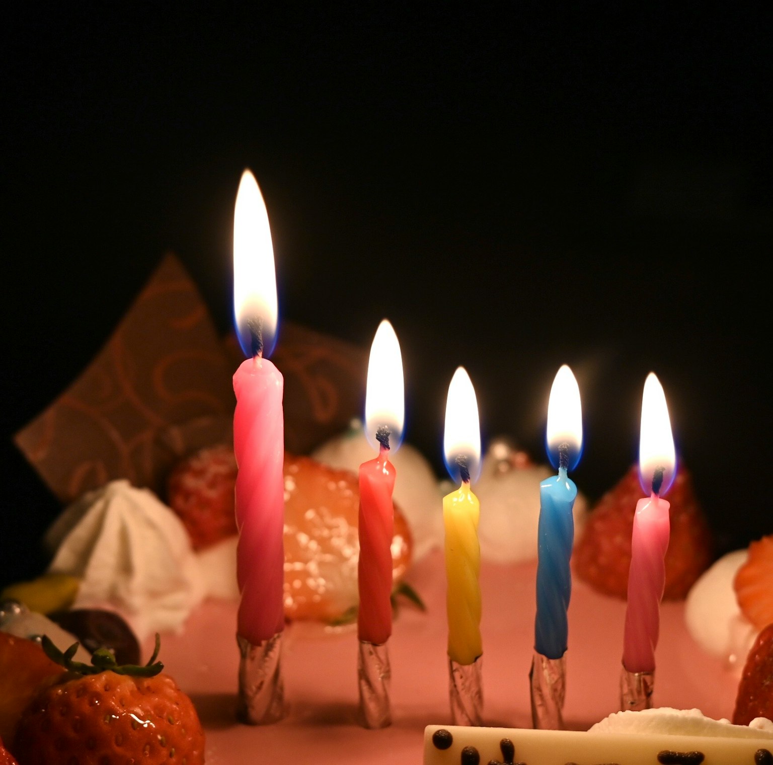 색색의 촛불이 켜진 케이크와 다양한 과자 클로즈업