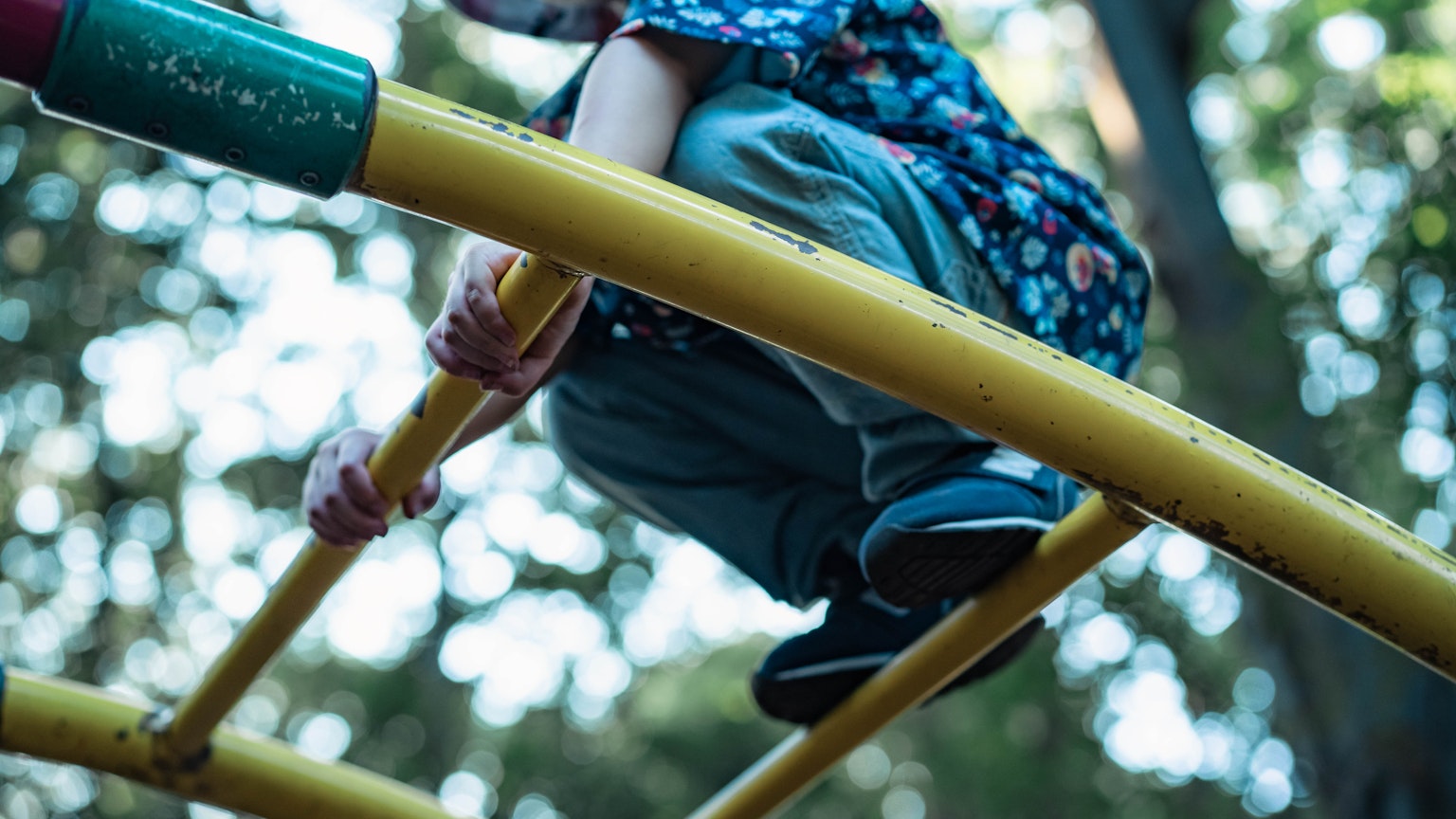 Anak duduk di batang permainan kuning di taman