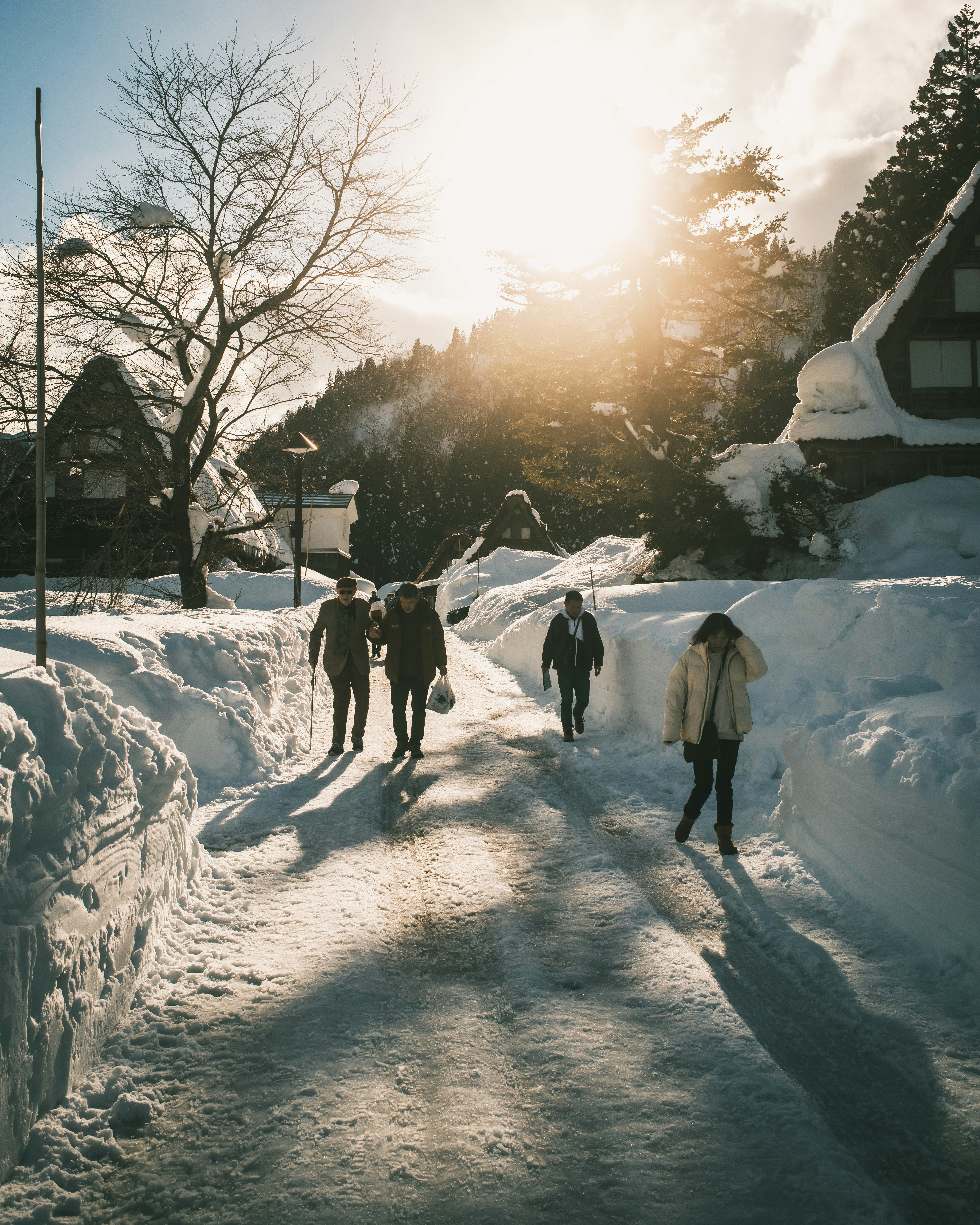 Des personnes marchant sur une route enneigée dans une région de fortes chutes de neige au lever du soleil