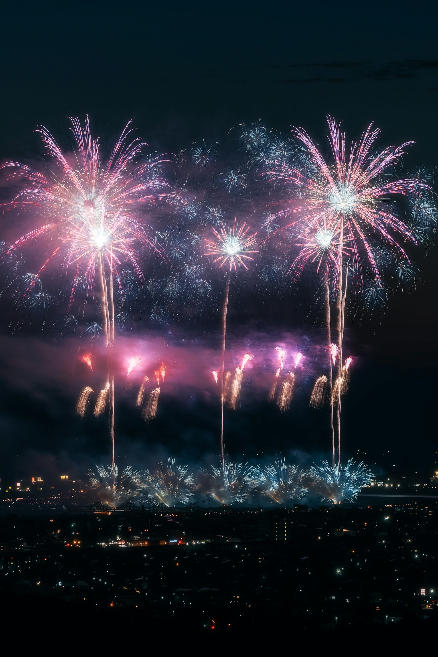 Fuochi d'artificio colorati esplodono nel cielo notturno su un paesaggio urbano