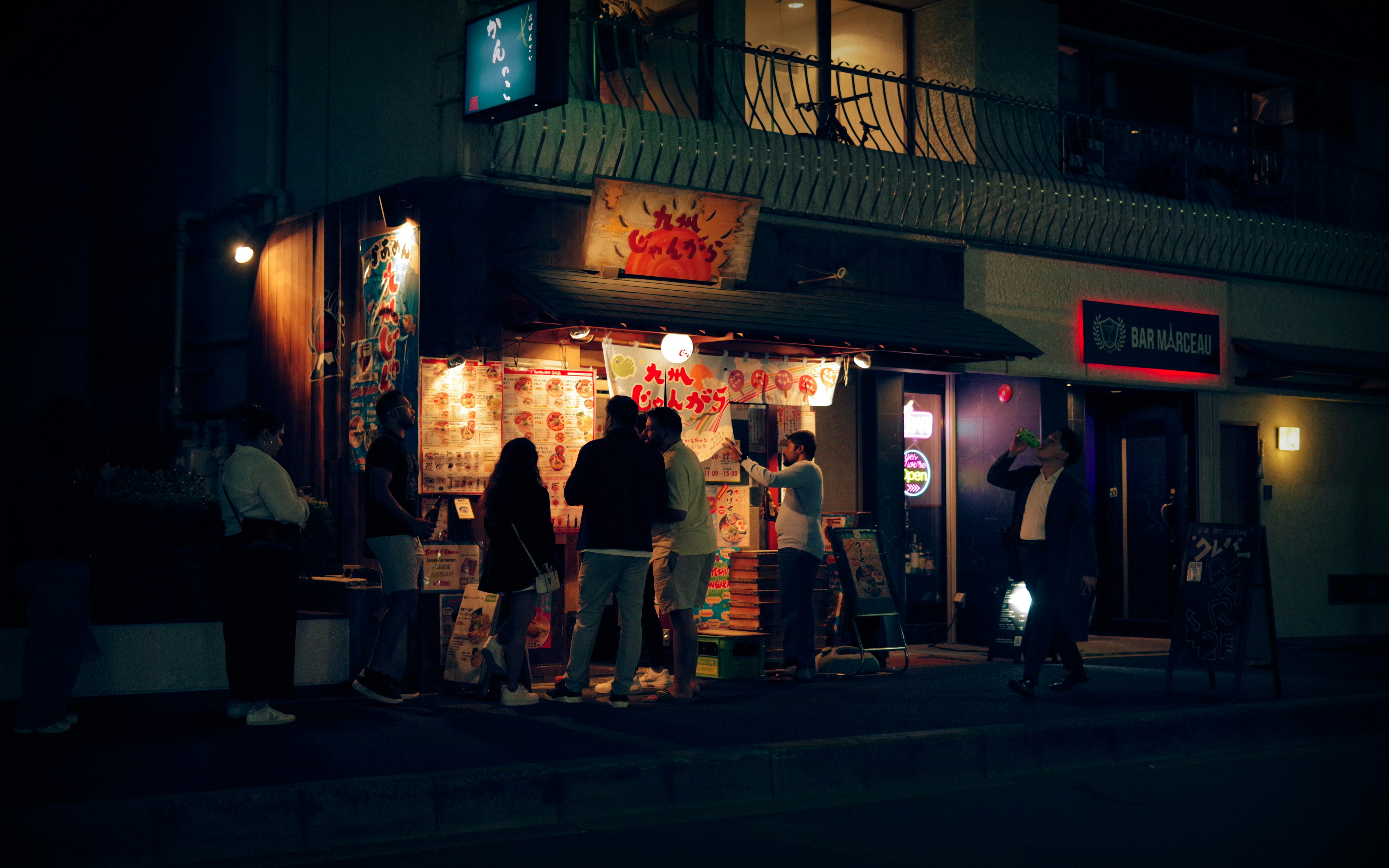 夜のラーメン店の看板と行き交う人々の街並み
