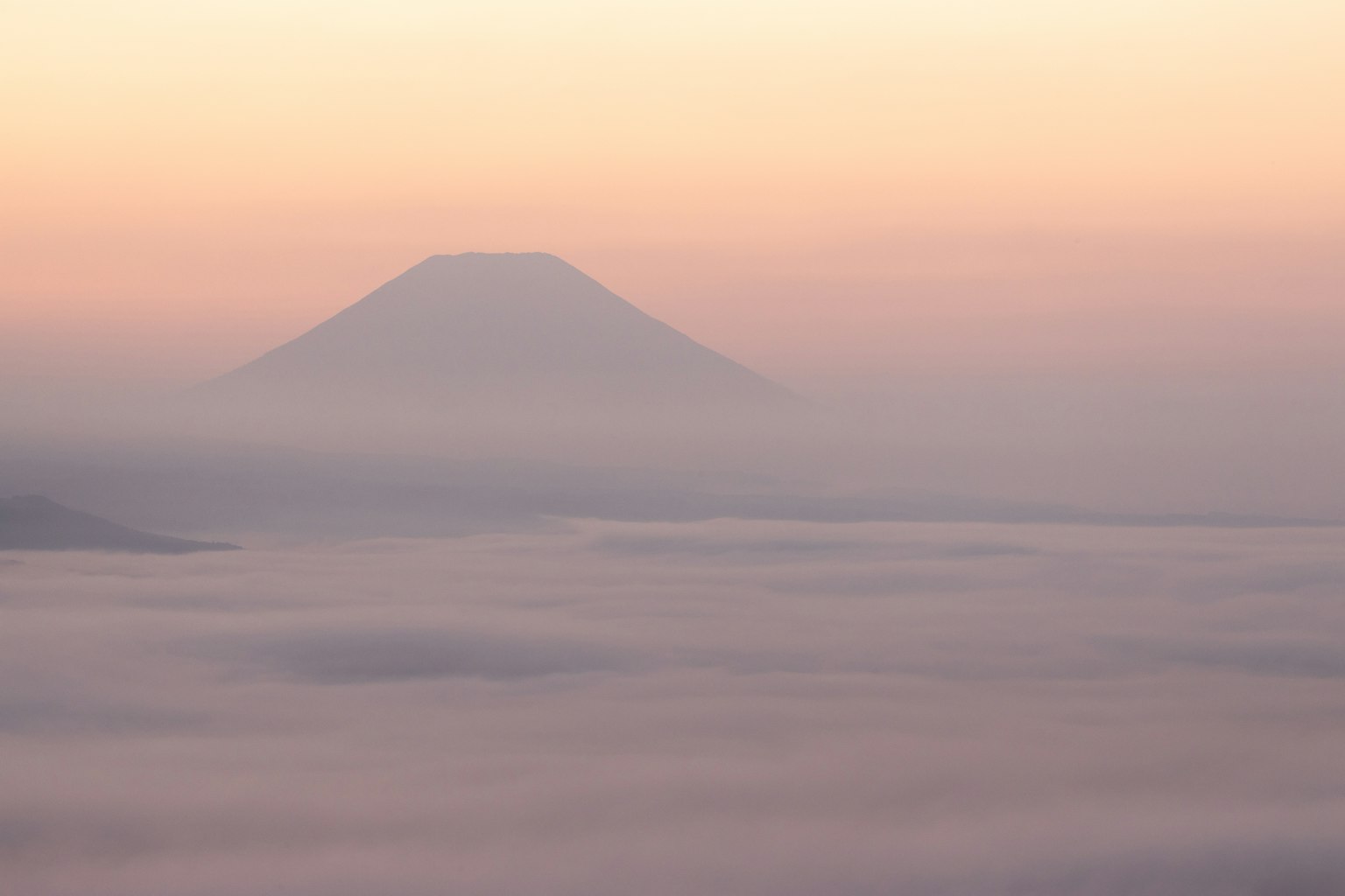 被雾气笼罩的富士山轮廓与柔和的粉彩天空