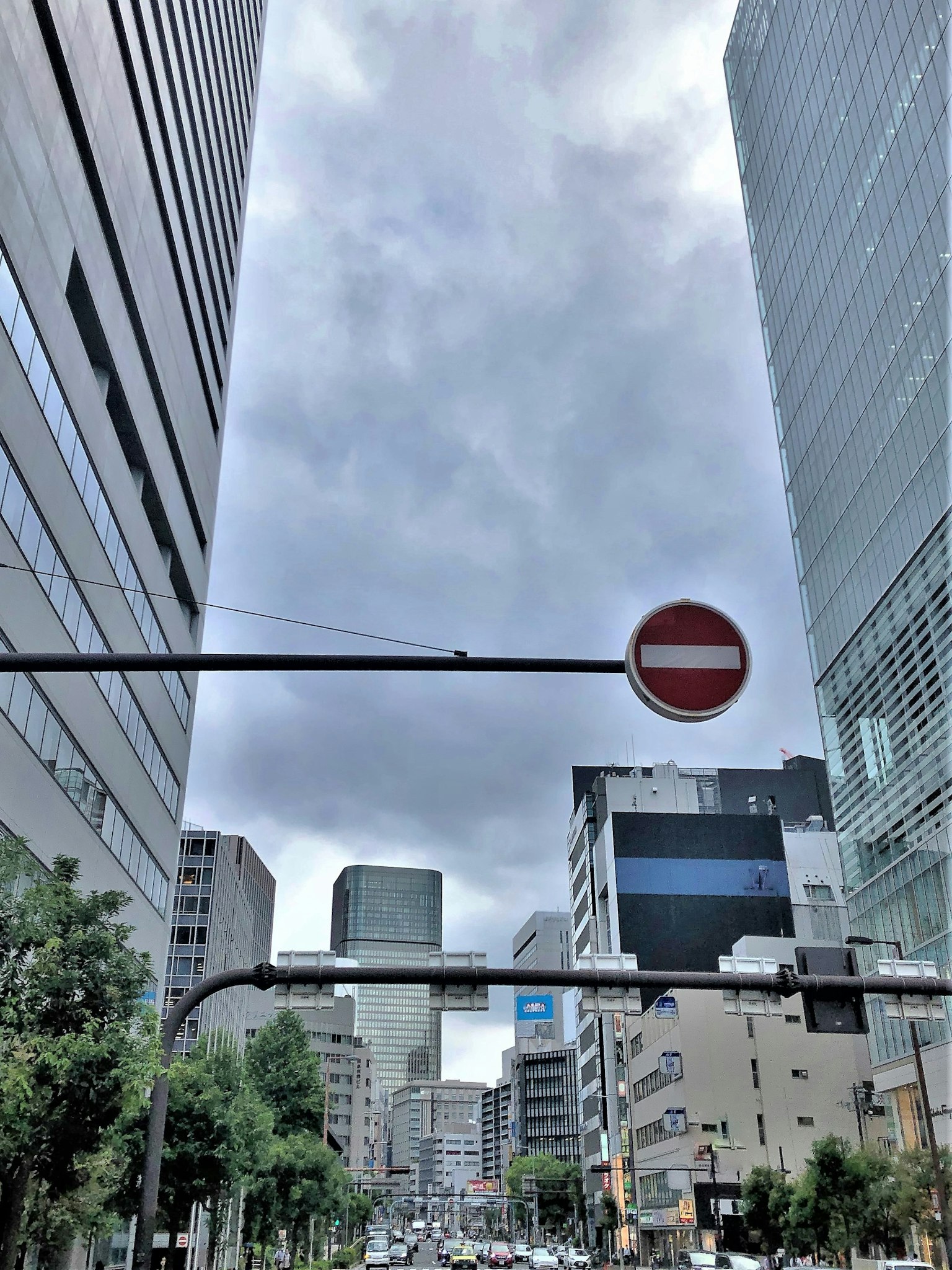 Vista del cielo nublado entre altos edificios con señal de tráfico