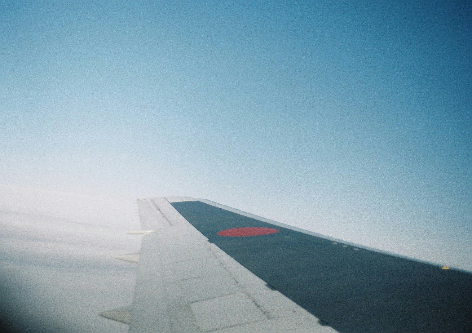 맑은 파란 하늘 아래 구름 위를 나는 비행기의 날개