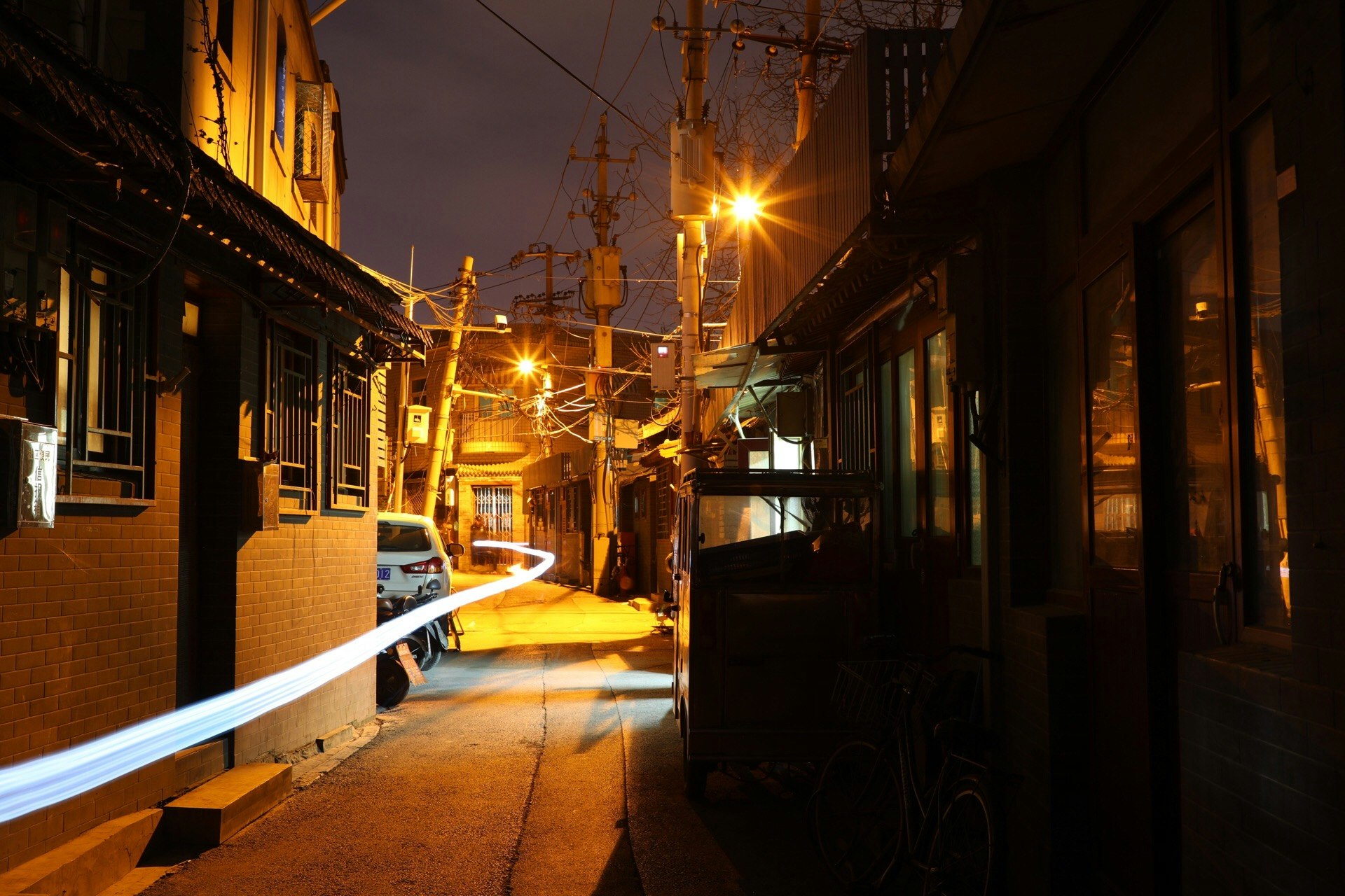 夜の路地に並ぶ街灯と電線のある商店街の通り