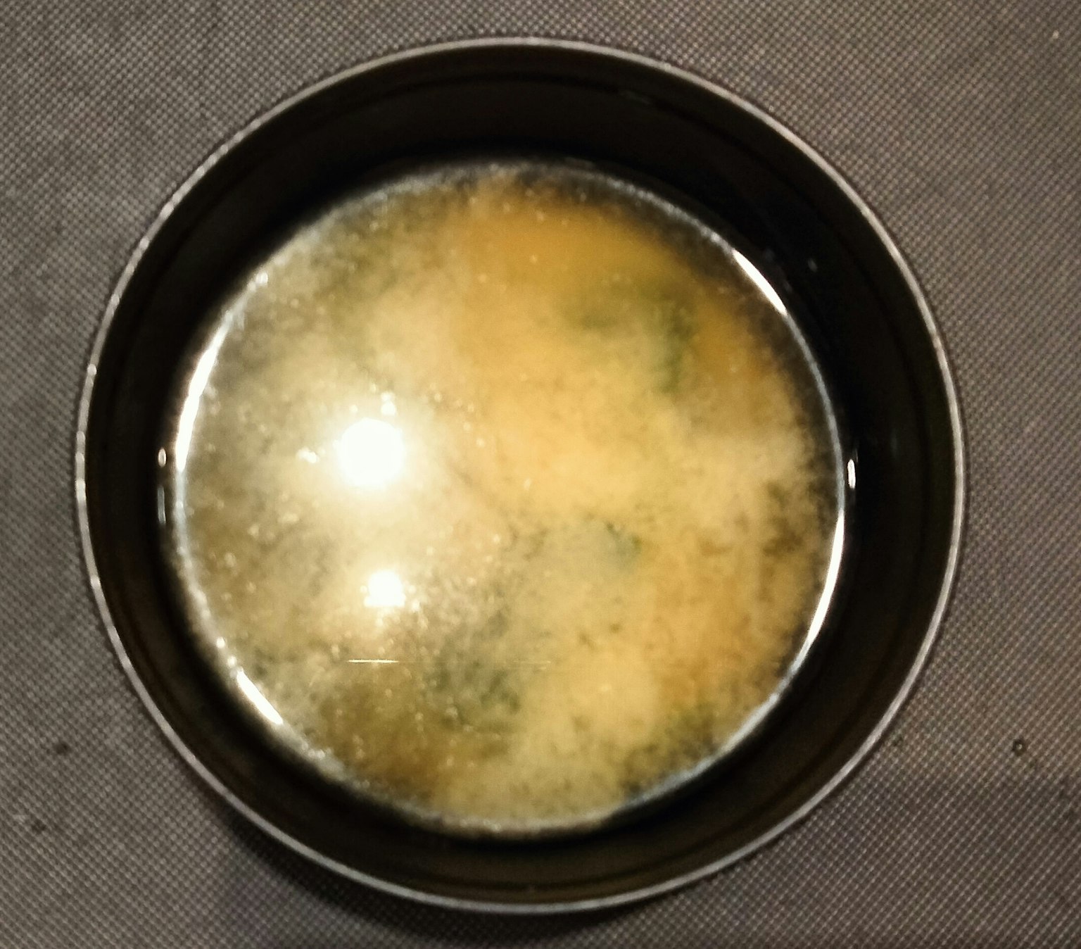 Zuppa di miso in una ciotola nera con una superficie liscia