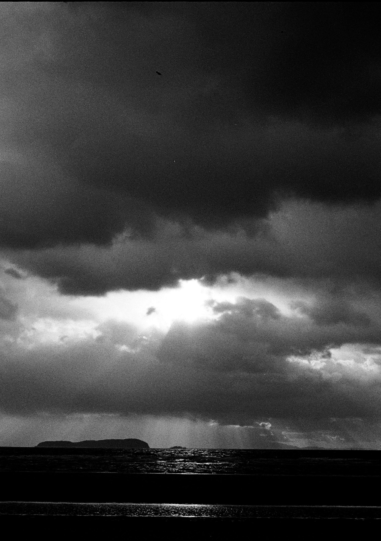 Un paesaggio con raggi di luce che attraversano nuvole scure sul mare