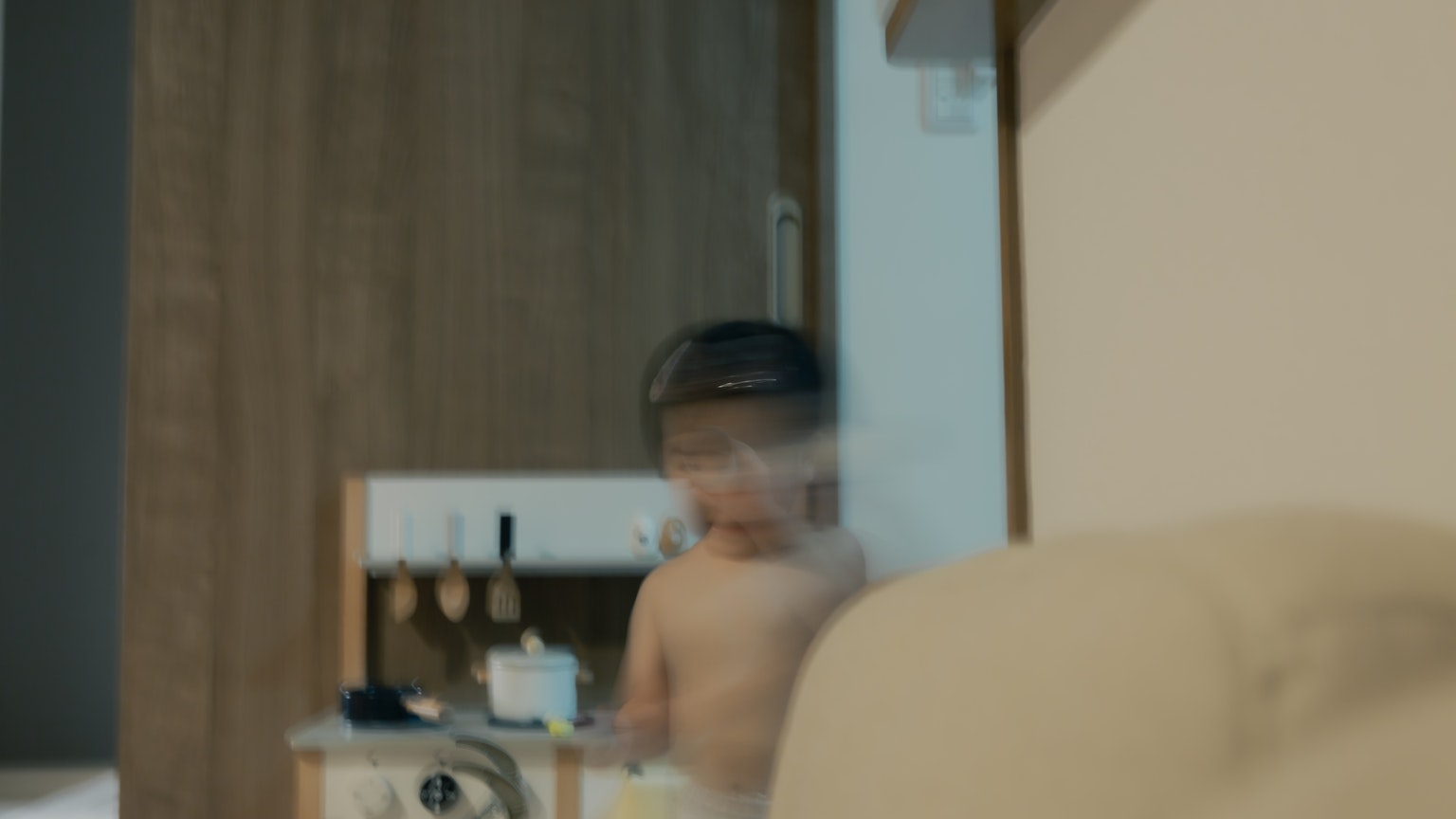 เด็กกำลังเล่นในห้องที่มีผนังและเฟอร์นิเจอร์ไม้