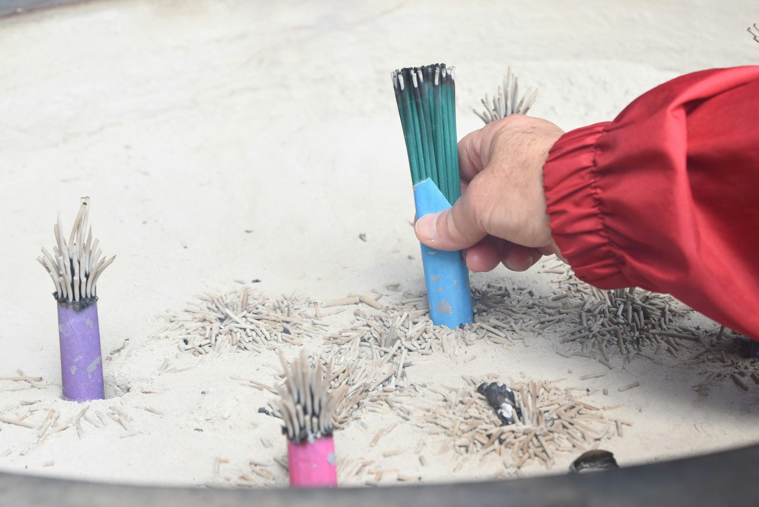 Một người cầm tay cầm màu xanh lấy một thanh màu từ cát
