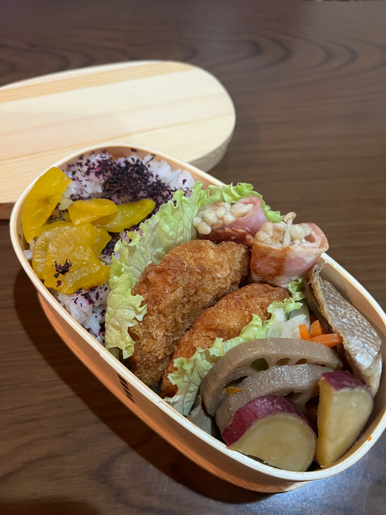 Hộp bento bằng gỗ đầy thực phẩm chiên và rau củ trộn