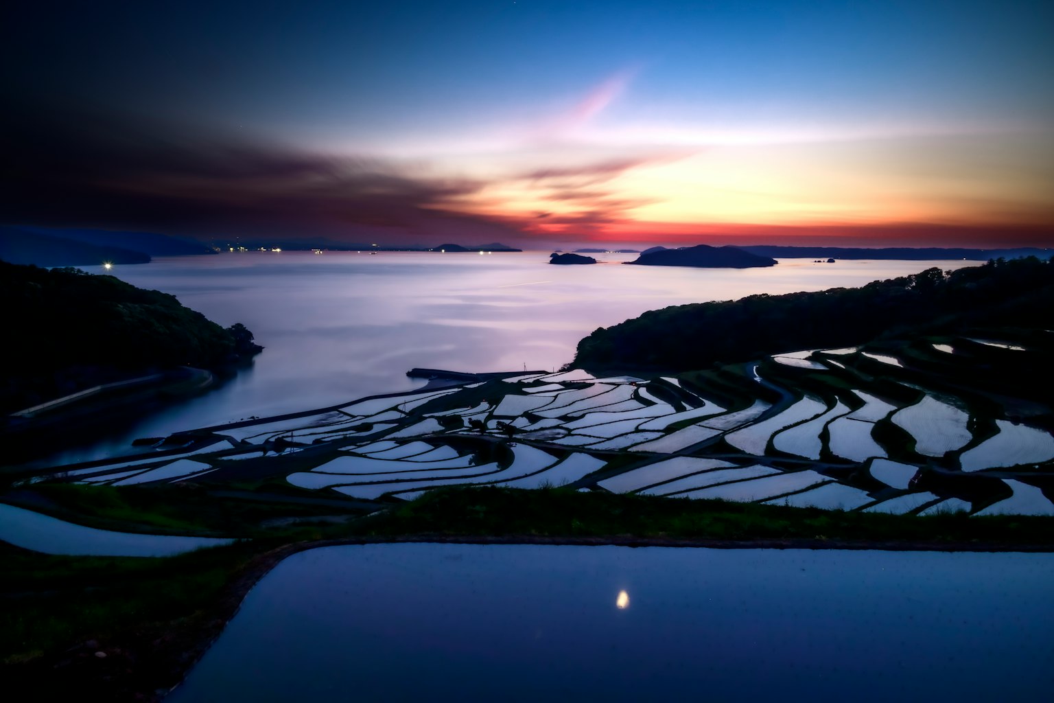 美しい夕焼けの中、棚田が水を反射している風景