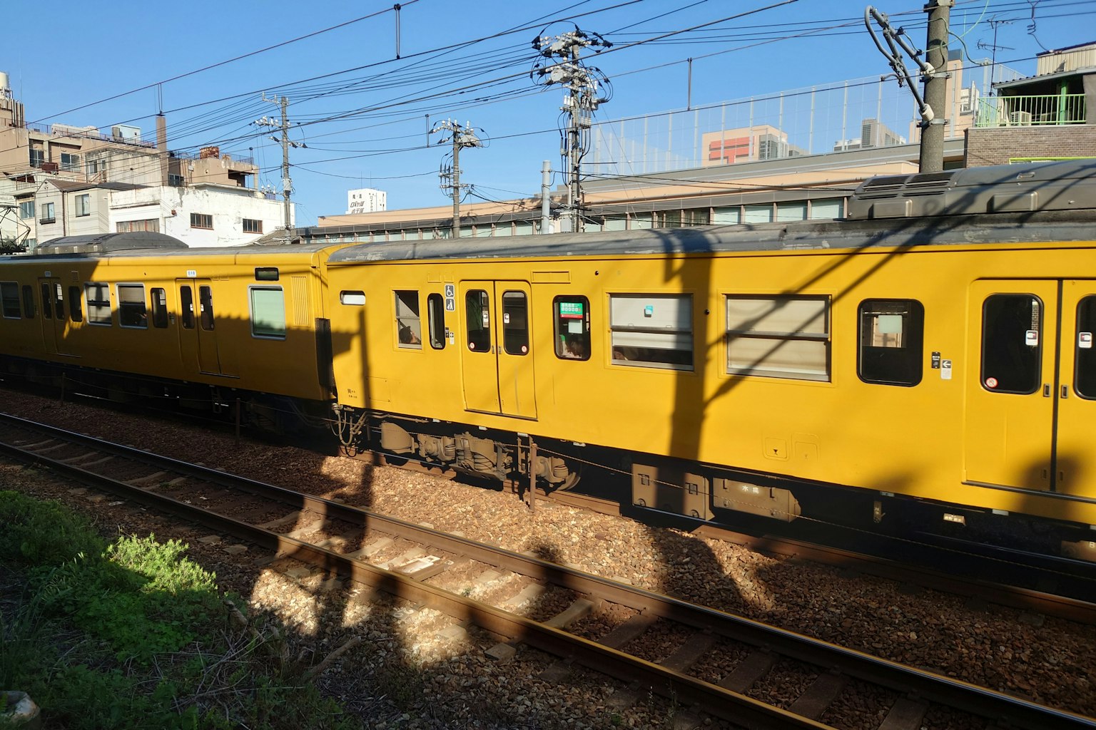 A yellow train on the tracks with a clear blue sky