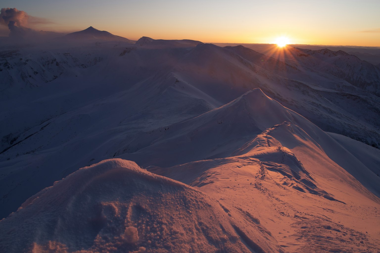 Montagne innevate con il sole che sorge sullo sfondo