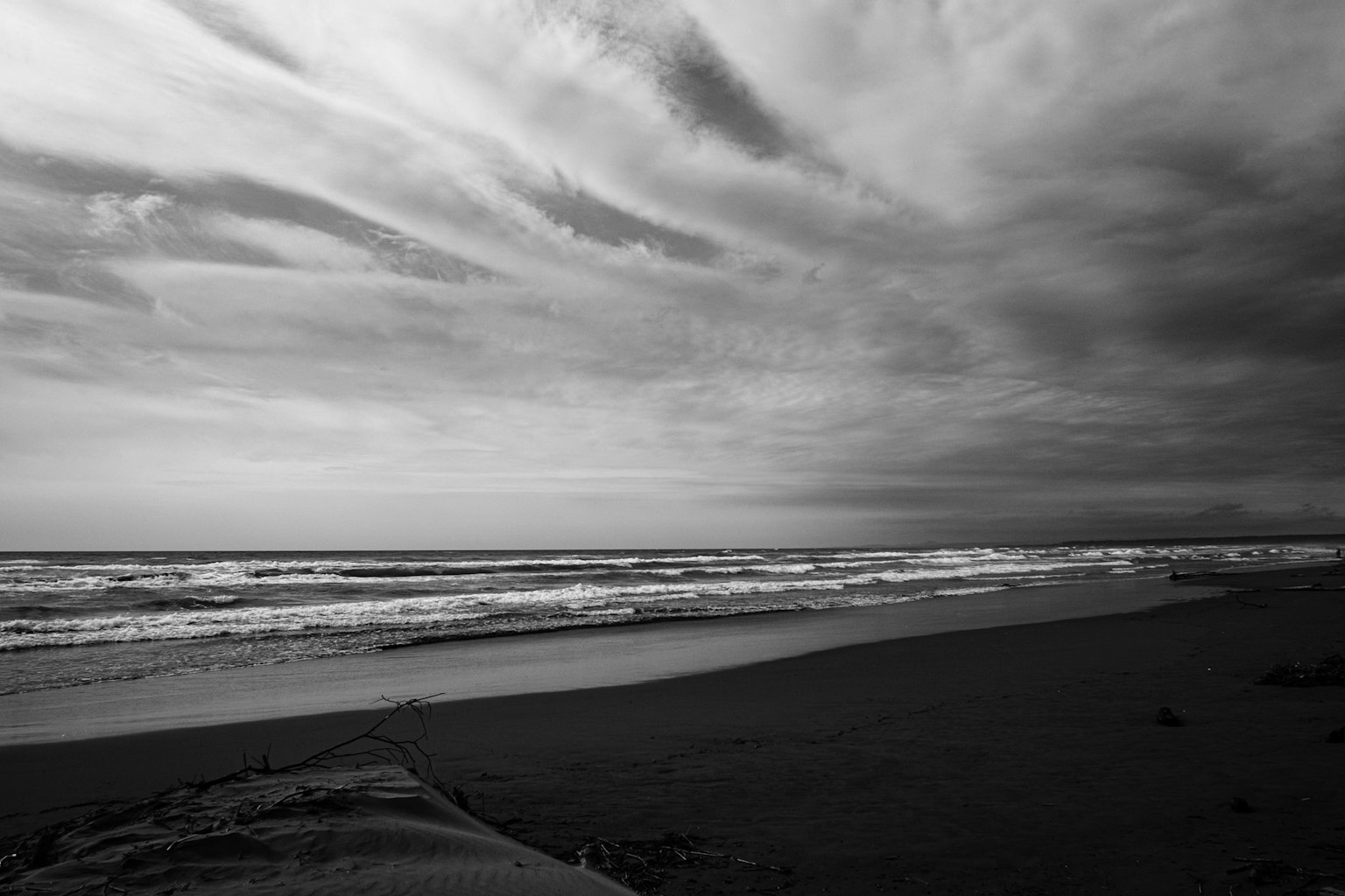 Schwarz-weiß Küstenlandschaft Wellen und Wolkenmuster schaffen eine dramatische Szene