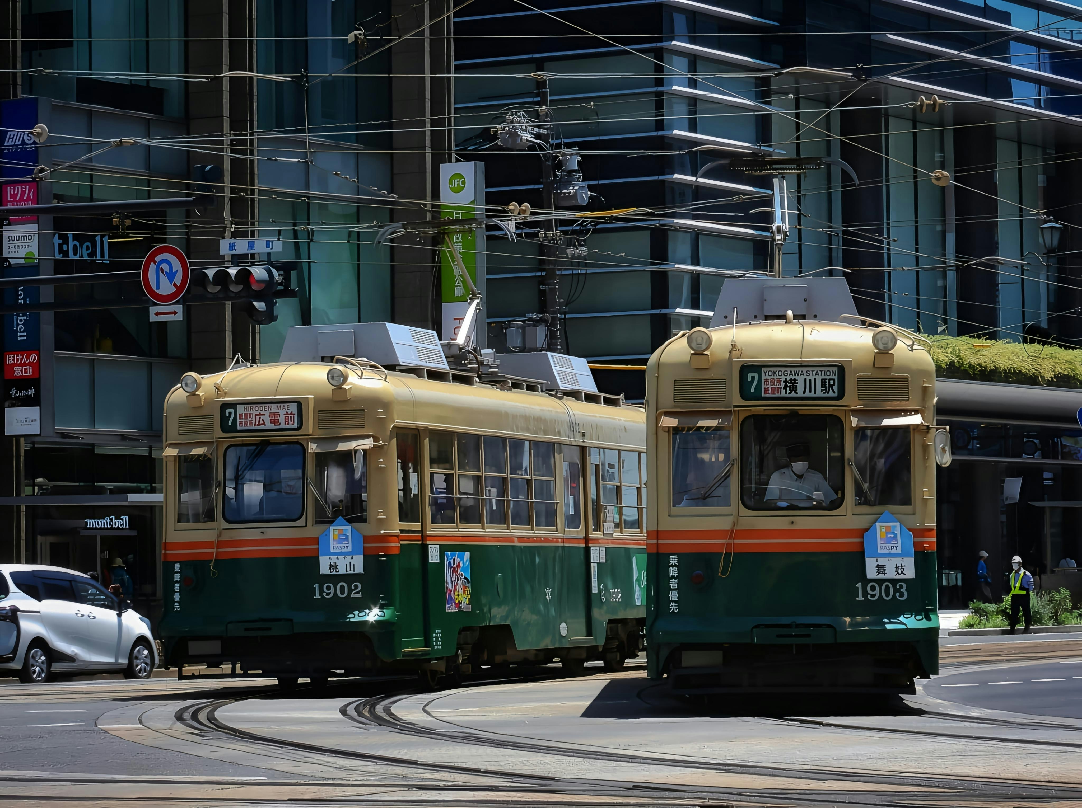 広島電鉄の路面電車（1902号・1903号）が交差点付近で行き違う様子