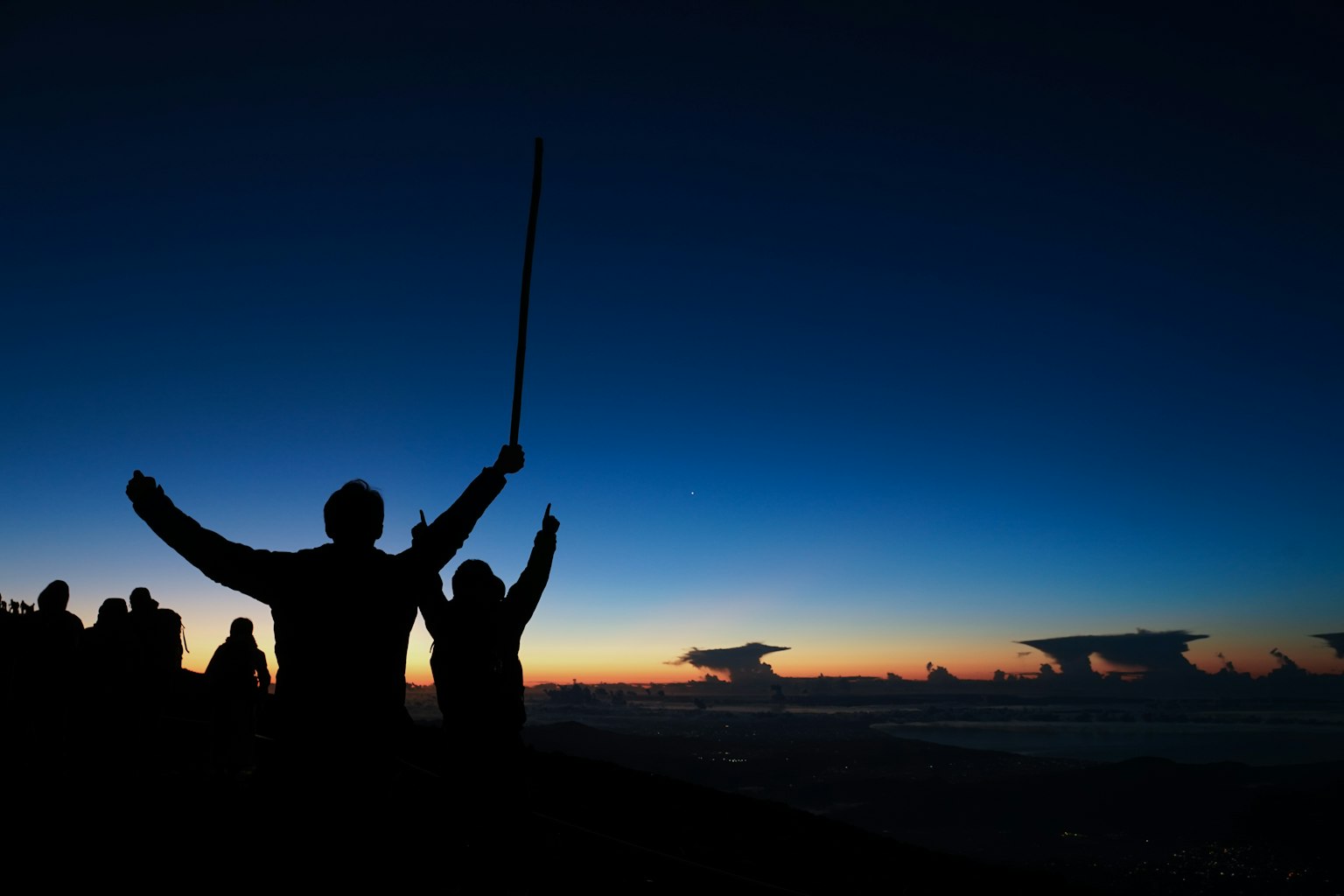 Silhouettes of people raising their arms at sunset with a gradient sky