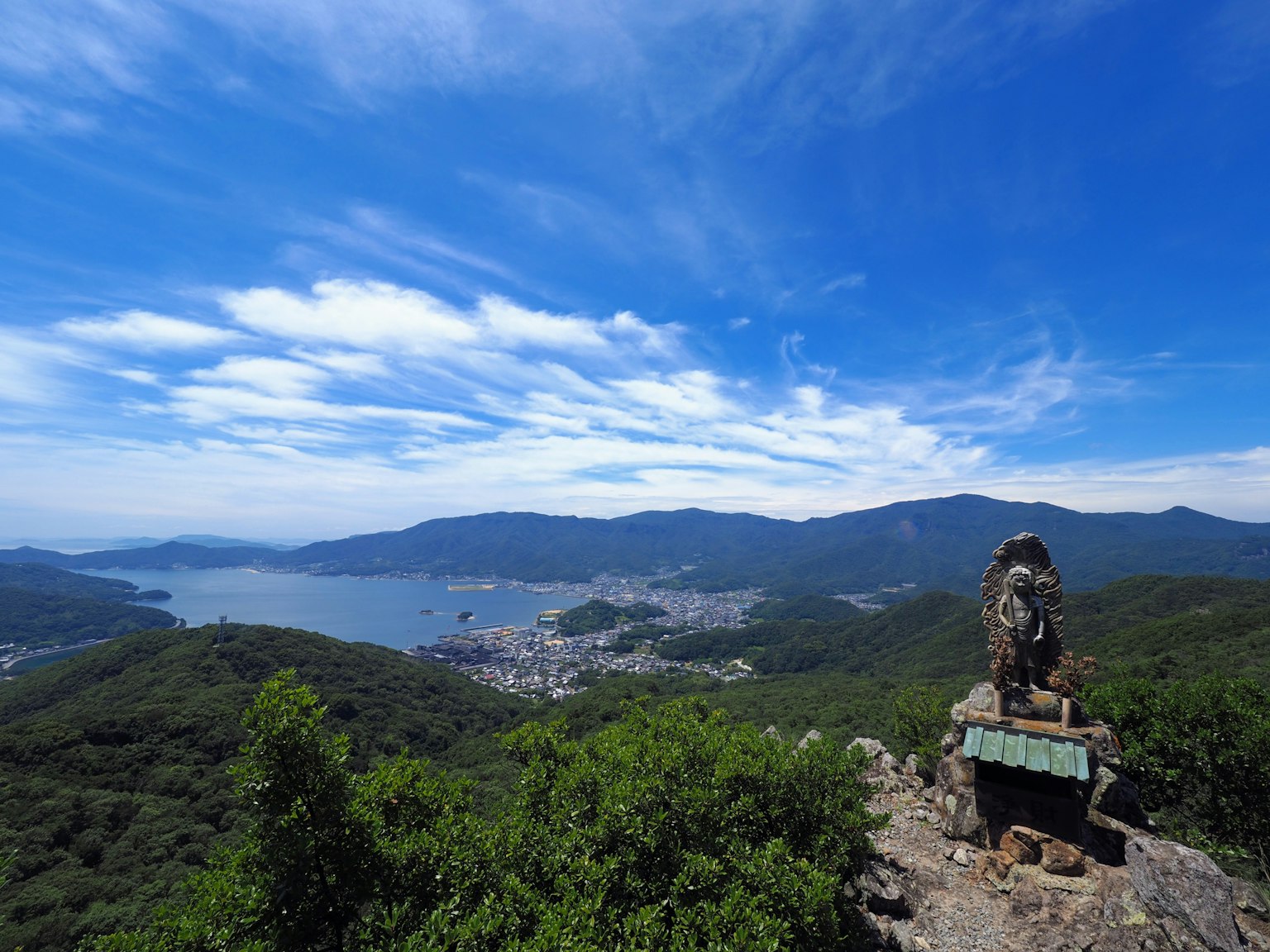 從山頂俯瞰海洋的美麗景色，前景有一座雕像