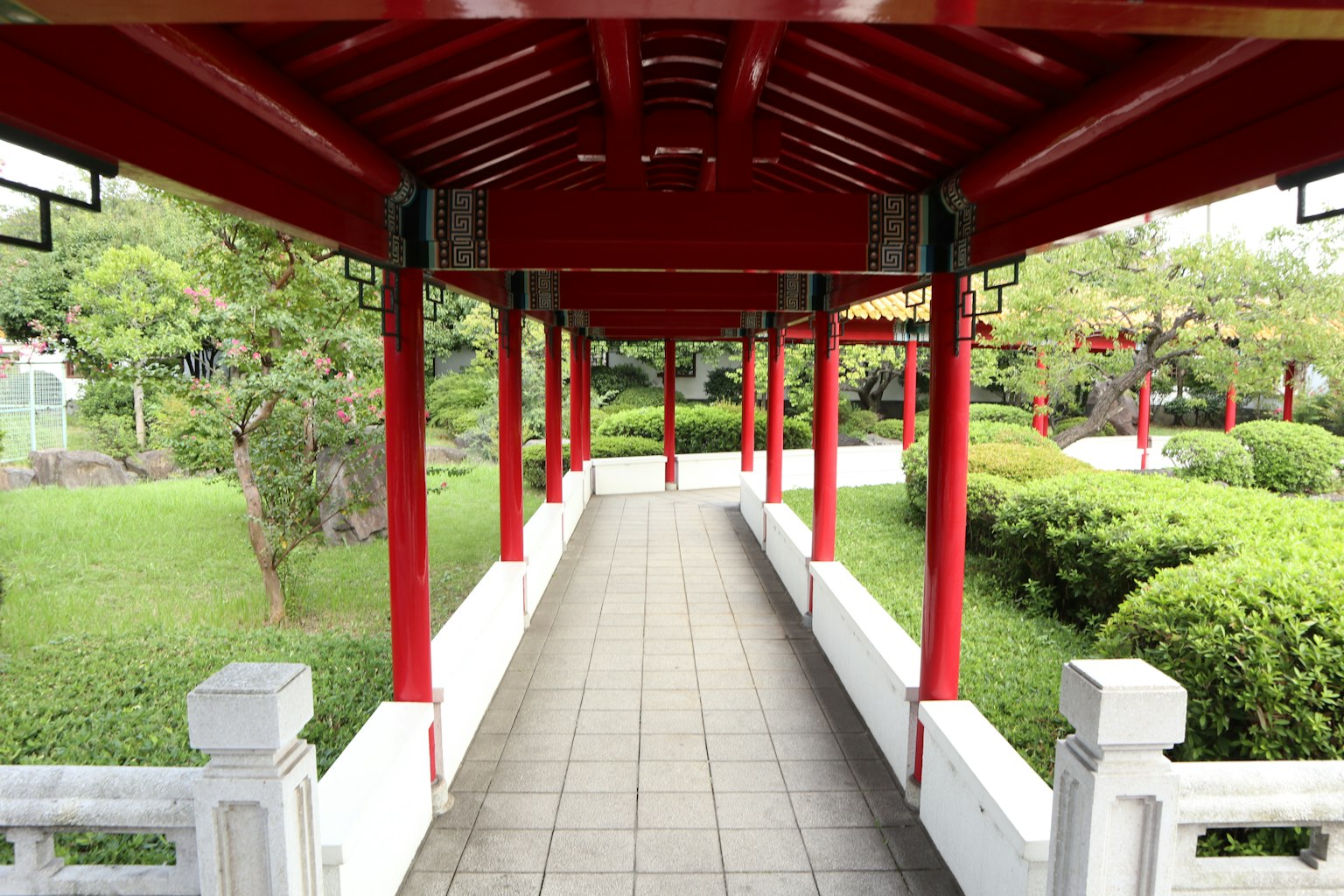 ทางเดินสวนที่มีเสาสีแดงและภูมิทัศน์สีเขียว