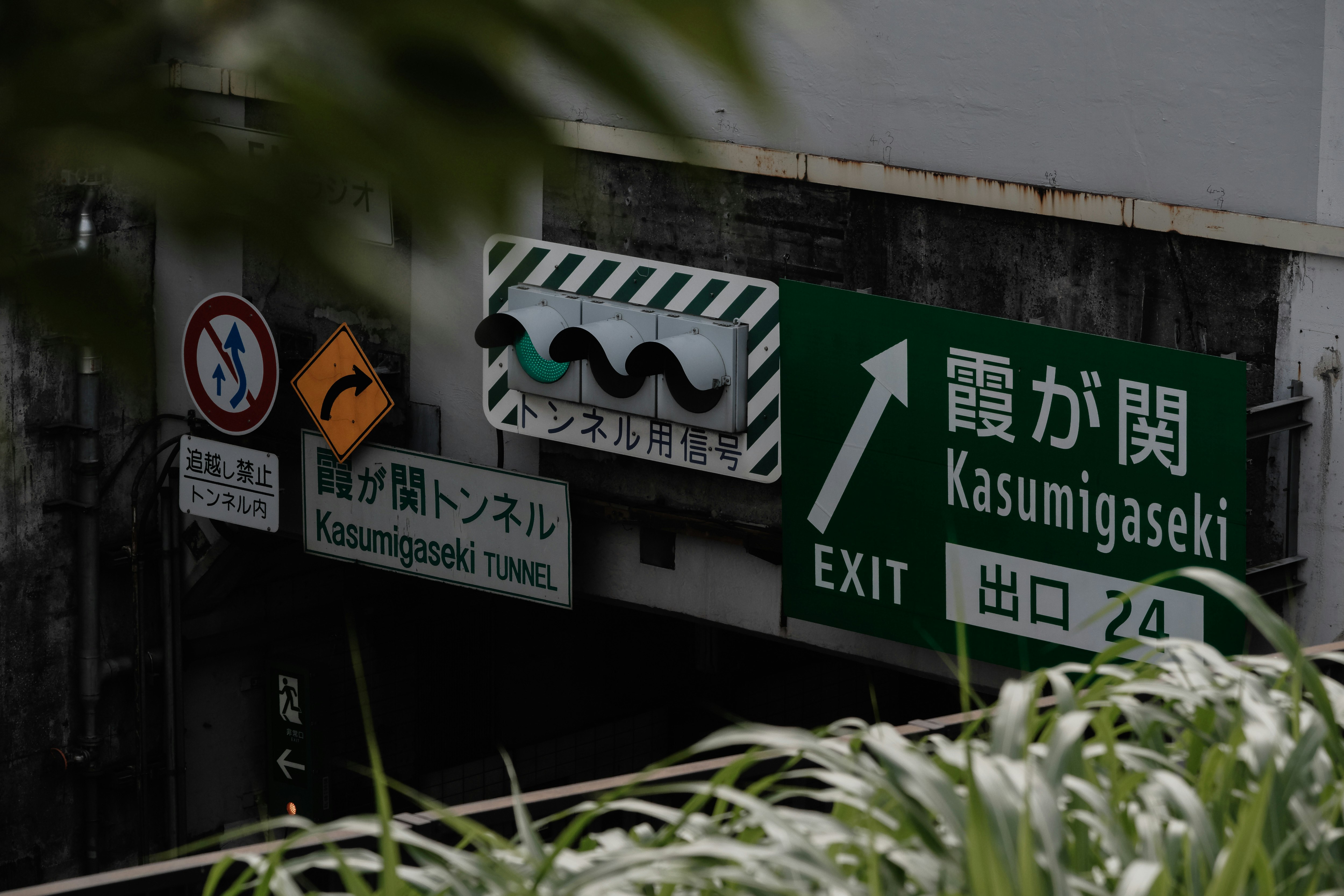 首都高の標識と出口表示がある高架下の壁面