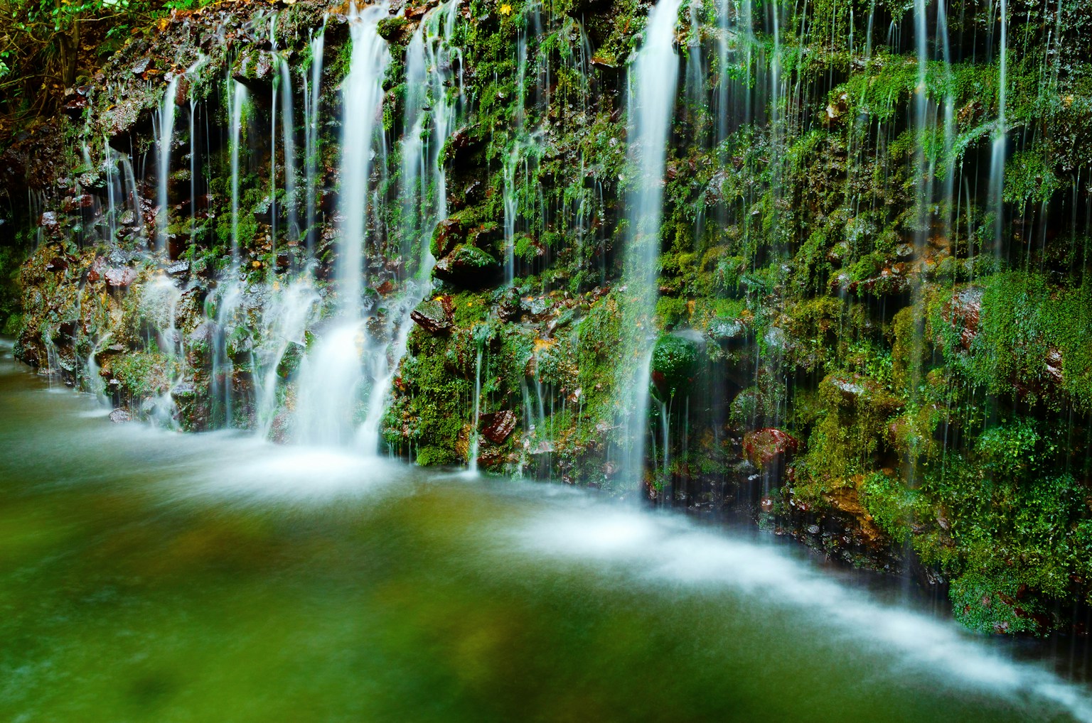 A beautiful scene of a waterfall cascading over moss-covered rocks